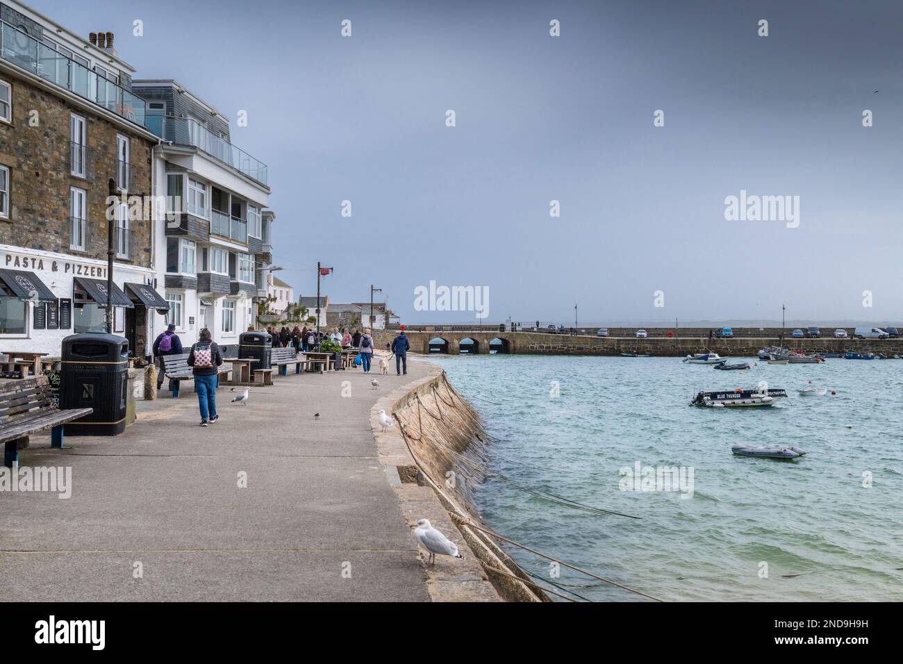 Wetter in Großbritannien. Besucher, die an der Wharf spazieren gehen, sind an einem kalten, erbärmlichen Tag in der historischen Küstenstadt St. Ives in Cornwall in England im Vereinigten Königreich. Stockfoto