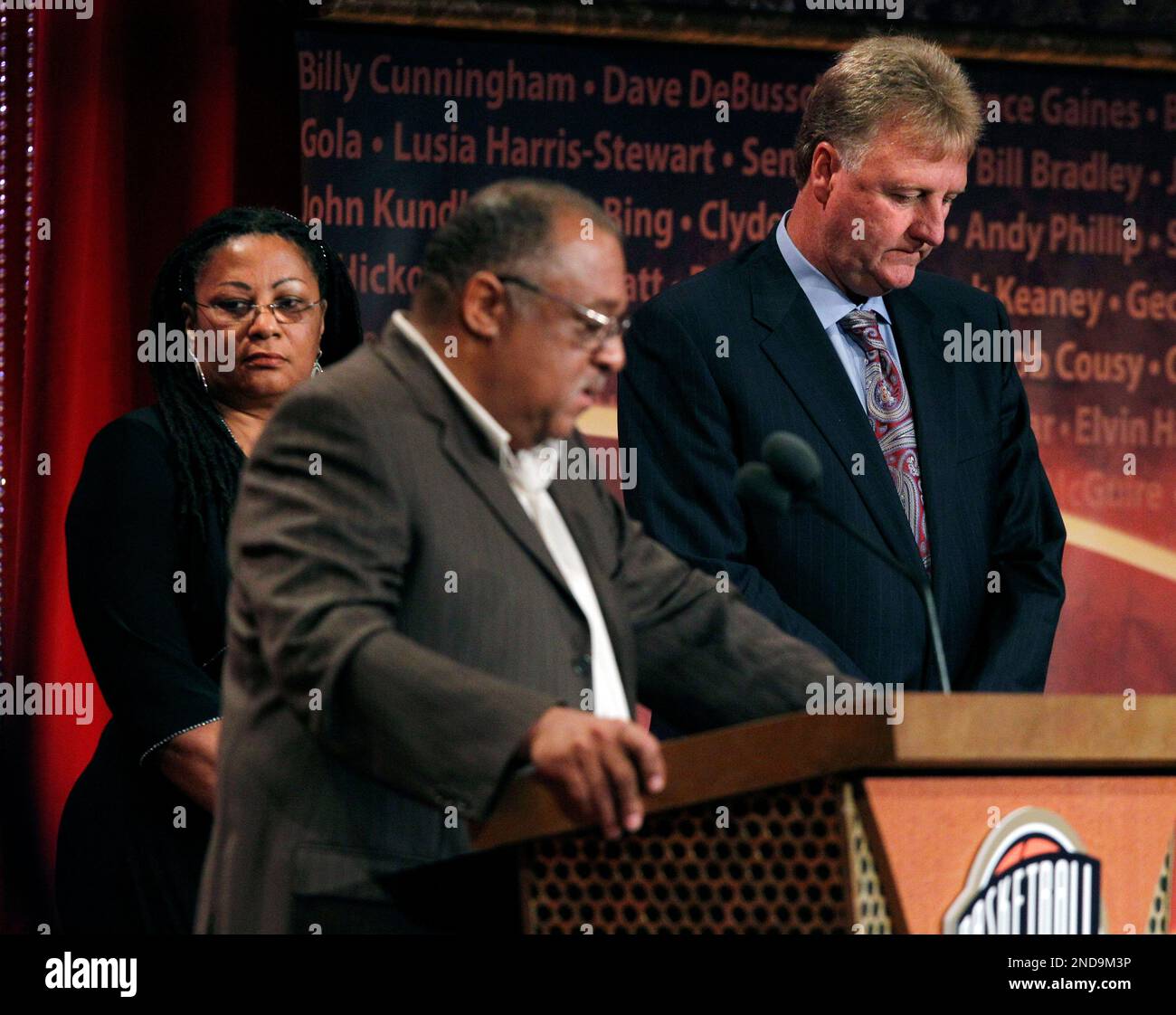 Former Boston Celtics player Larry BIrd, right, and Donna Johnson, left, widow of Basketball Hall of Fame inductee Dennis Johnson, listen as Dennis' brother Gary Johnson speaks while Dennis is inducted posthumously during enshrinement ceremonies in Springfield, Mass., Friday, Aug. 13, 2010. (AP Photo/Elise Amendola) Stockfoto