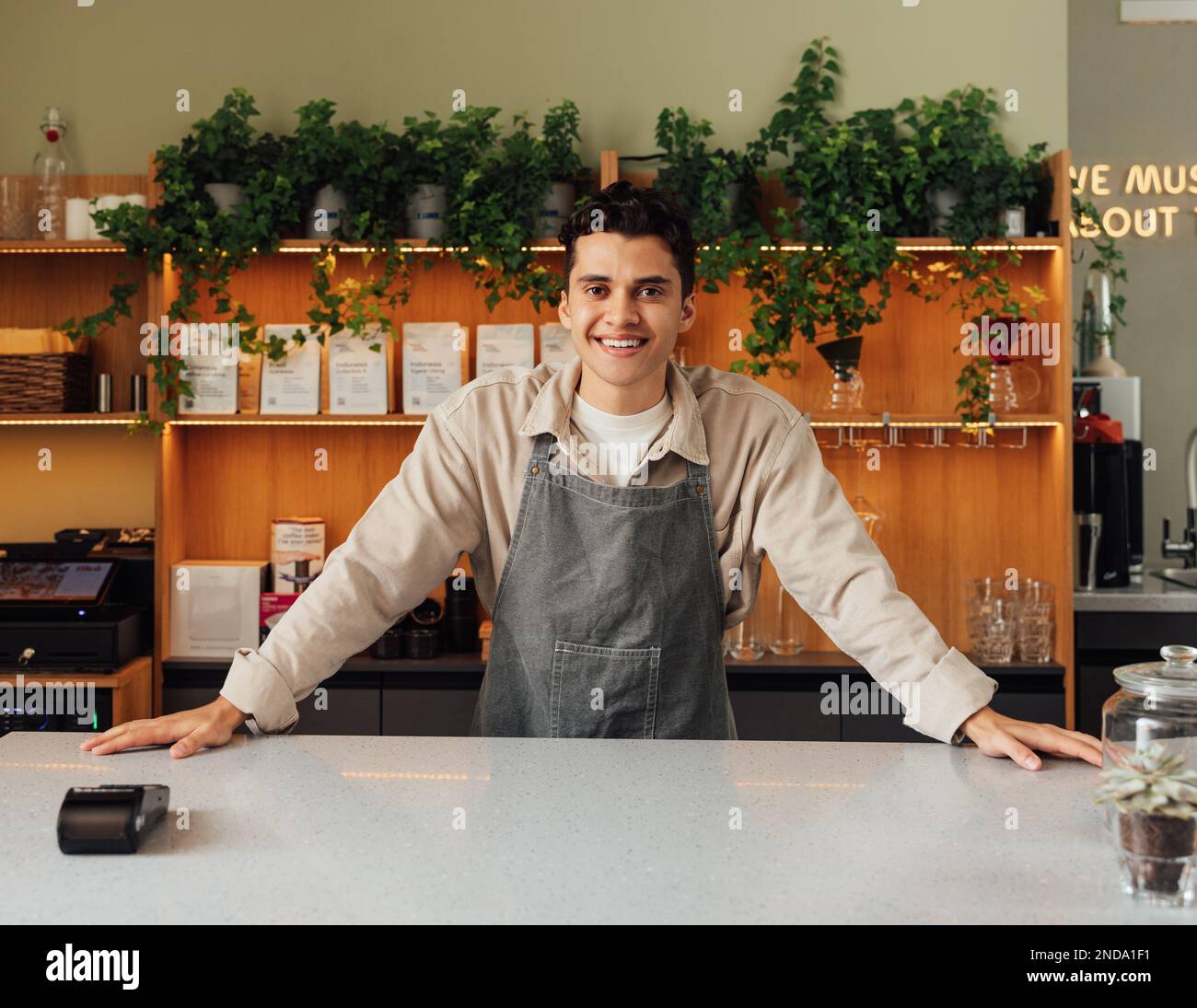 Lächelnder Coffee Shop Besitzer an der Bar. Selbstbewusster Barista, der in die Kamera schaut. Stockfoto
