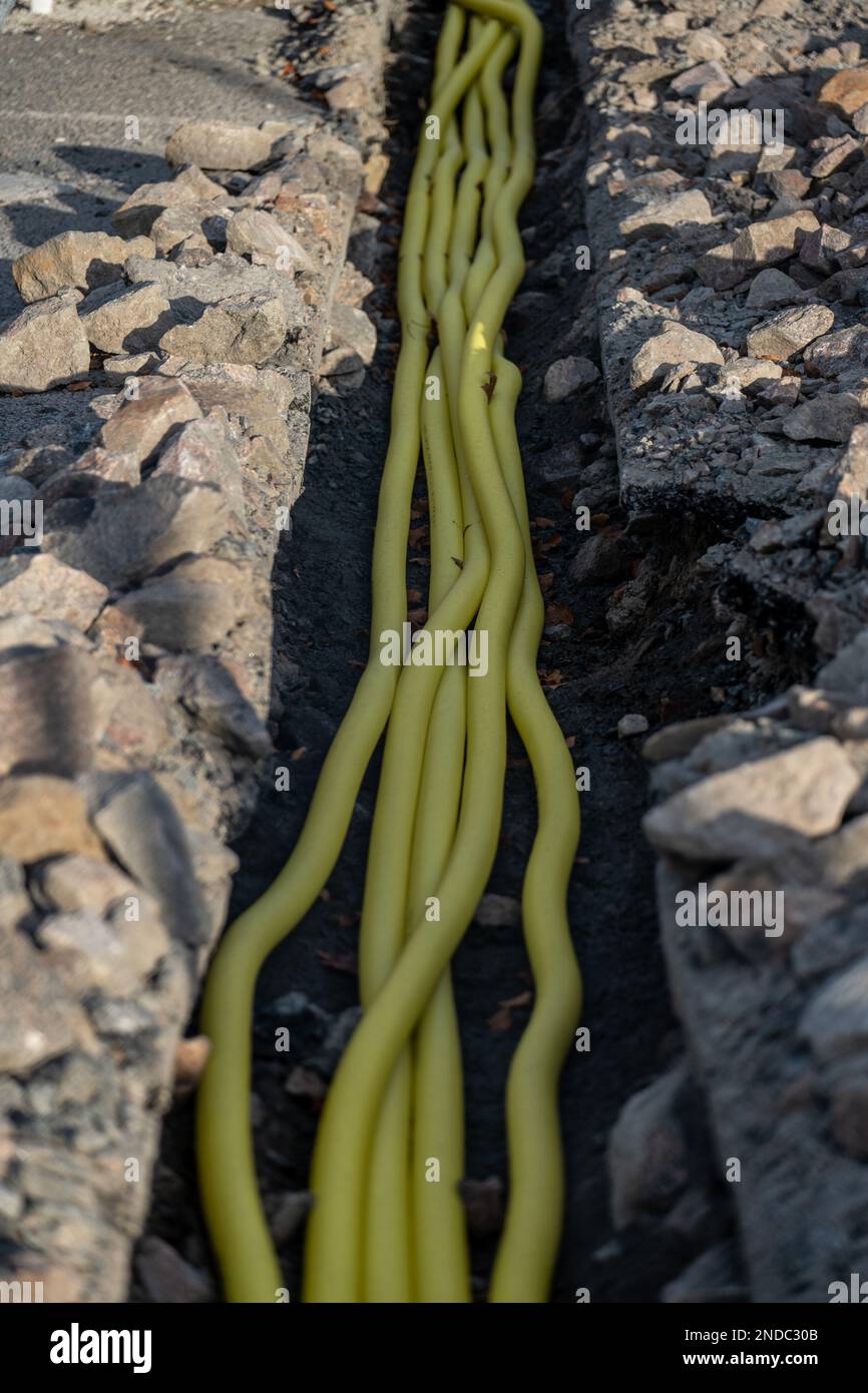 Graben mit gelben Versorgungsleitungen, die Strom zu Ladegeräten für Elektroautos führen Stockfoto