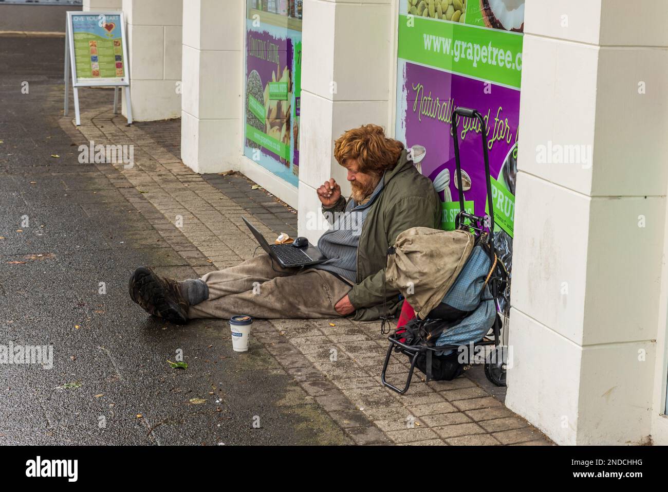 Ein Obdachloser saß mit einem Laptop auf dem Boden Stockfoto