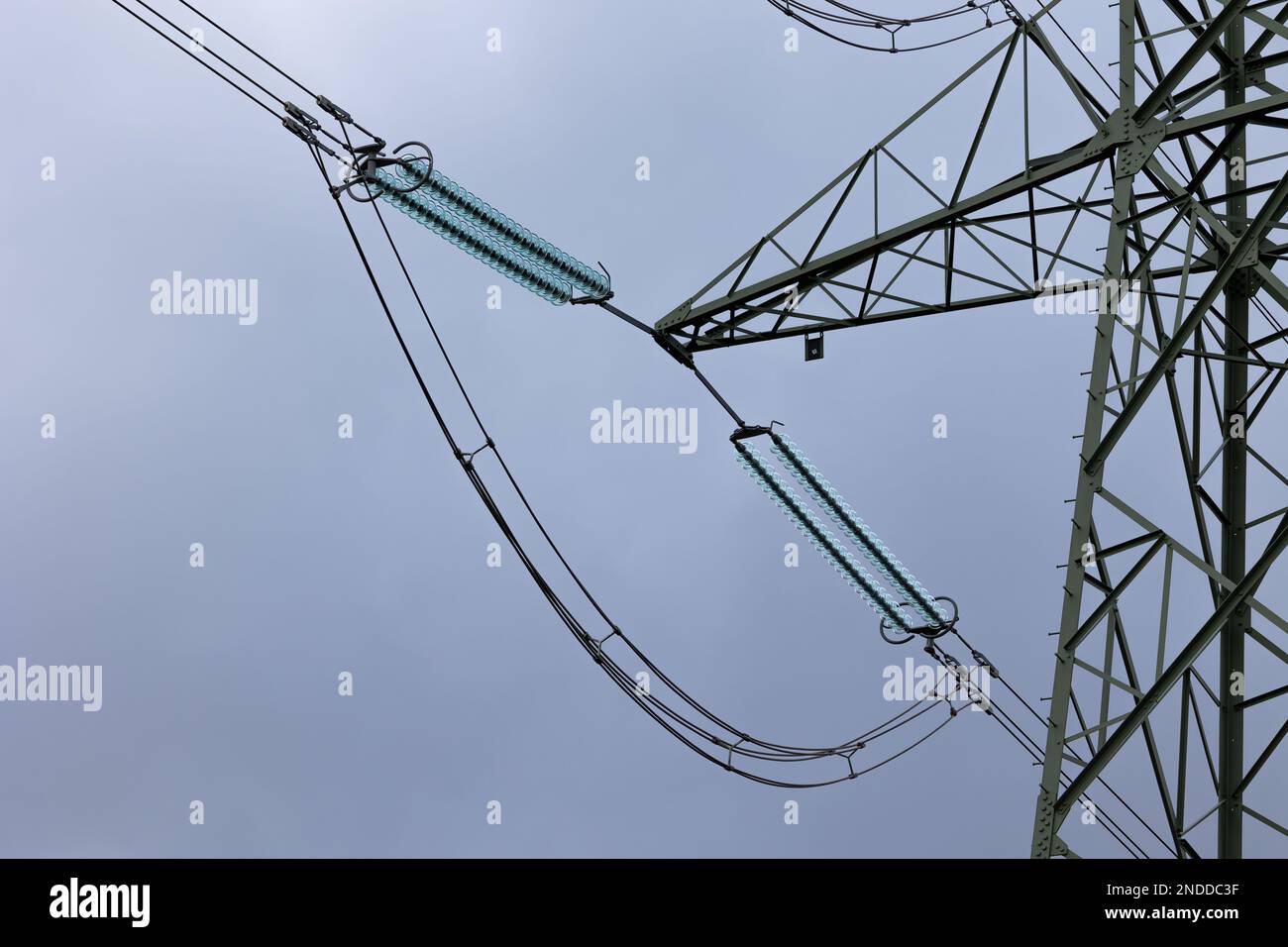 Nahaufnahme von Isolatoren an Hochspannungsmasten vor einem bewölkten Himmel. Hochspannungsleitungen Stockfoto