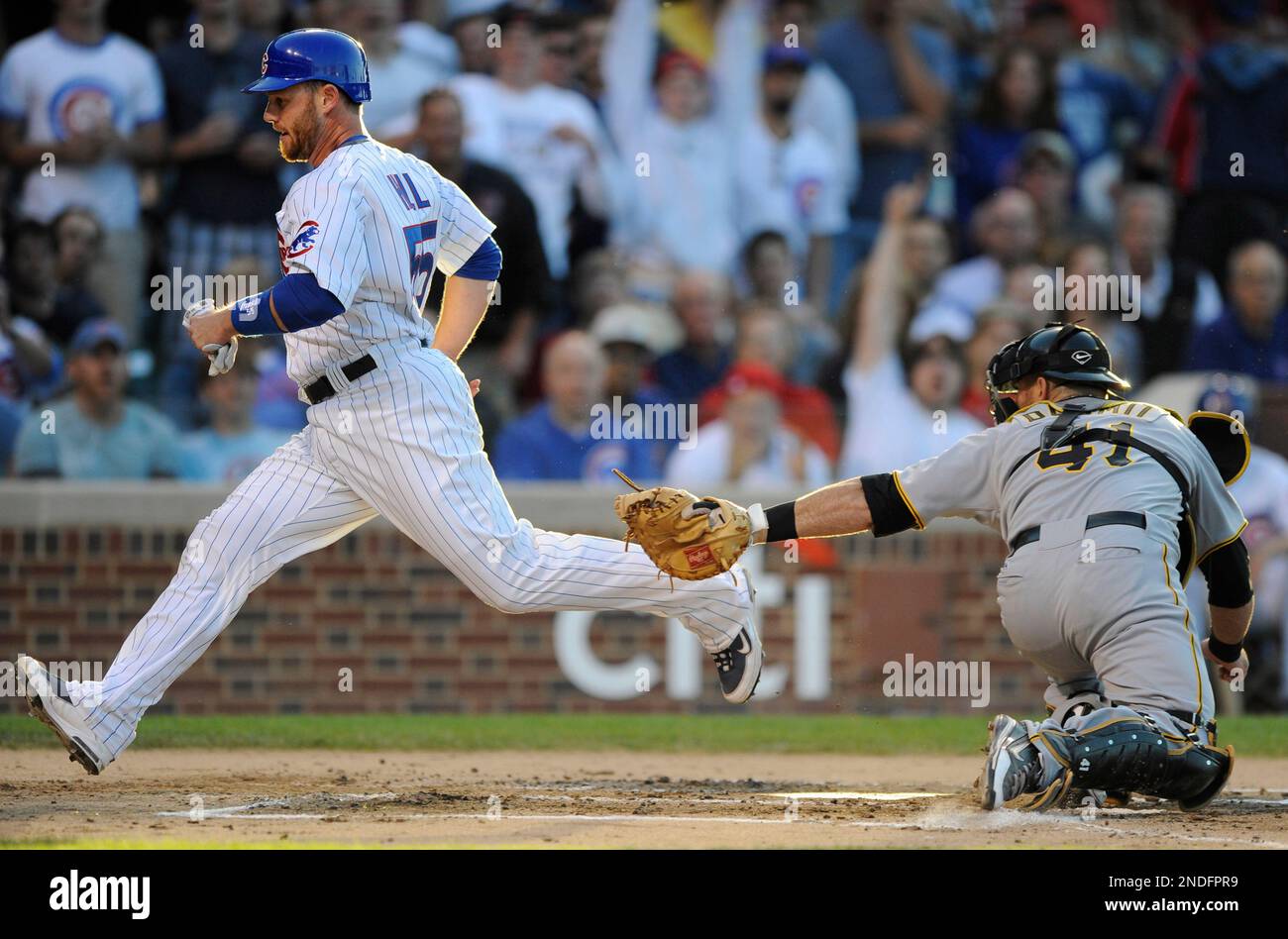Chicago Cubs' Koyie Hill left, scores as Pittsburgh Pirates catcher Ryan Doumit tries to apply the tag in the second inning of a baseball in Chicago, Tuesday, June 29, 2010. (AP Photo/Paul Beaty) Stockfoto