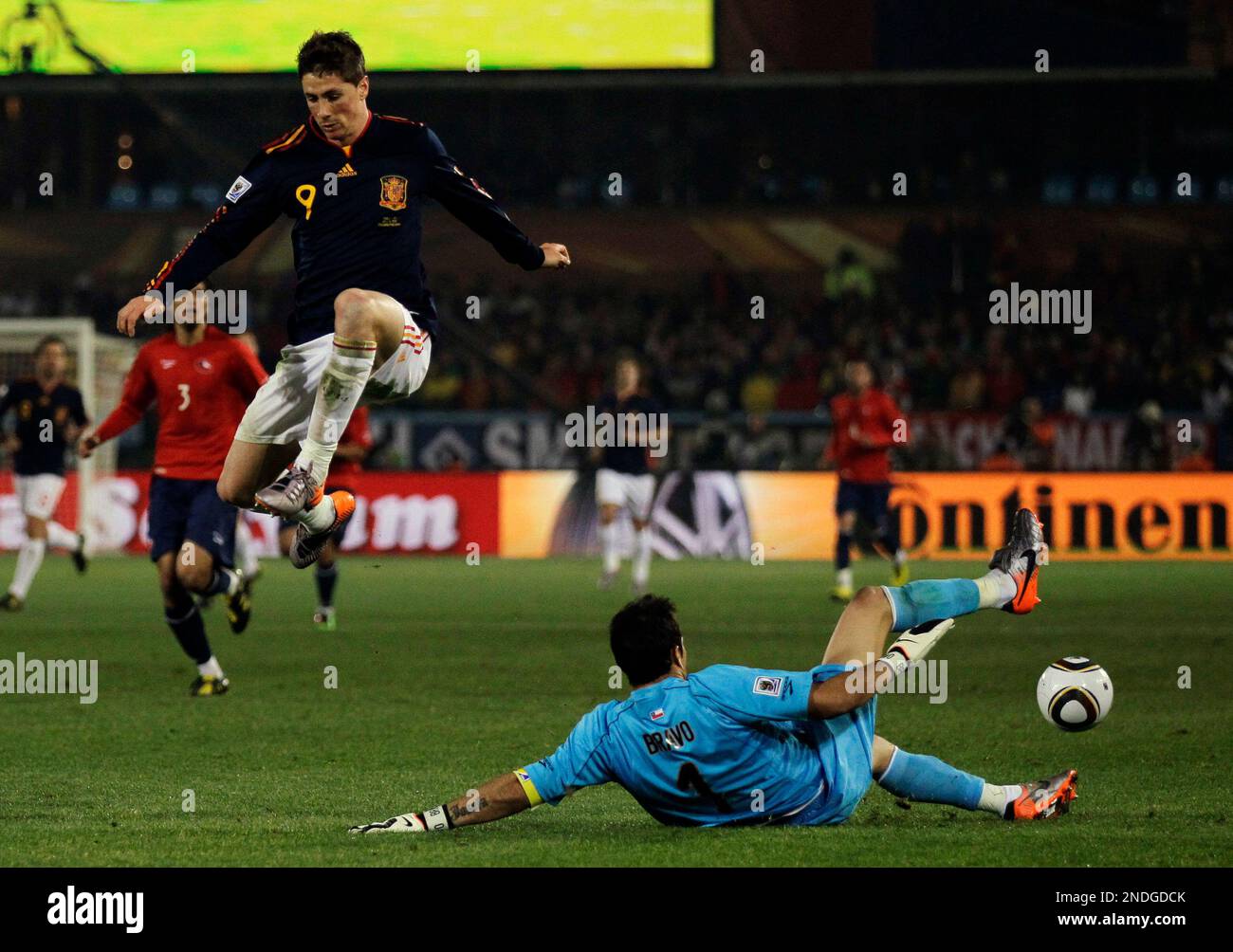 Spain's Fernando Torres, left, jumps over Chile goalkeeper Claudio Bravo, right, as his shot is deflected, setting up a goal by Spain's David Villa, not visible, during the World Cup group H soccer match between Chile and Spain at the Loftus Versfeld Stadium in Pretoria, South Africa, Friday, June 25, 2010. (AP Photo/Matt Dunham) Stockfoto