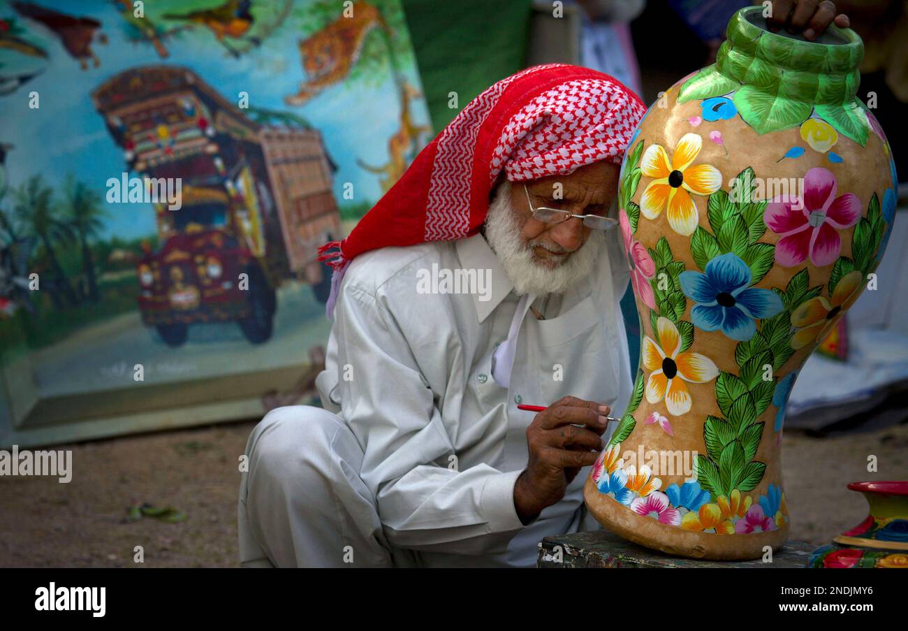 Pakistani artist HabiburRehman paints traditional art on a vase at his stall during a Punjab
