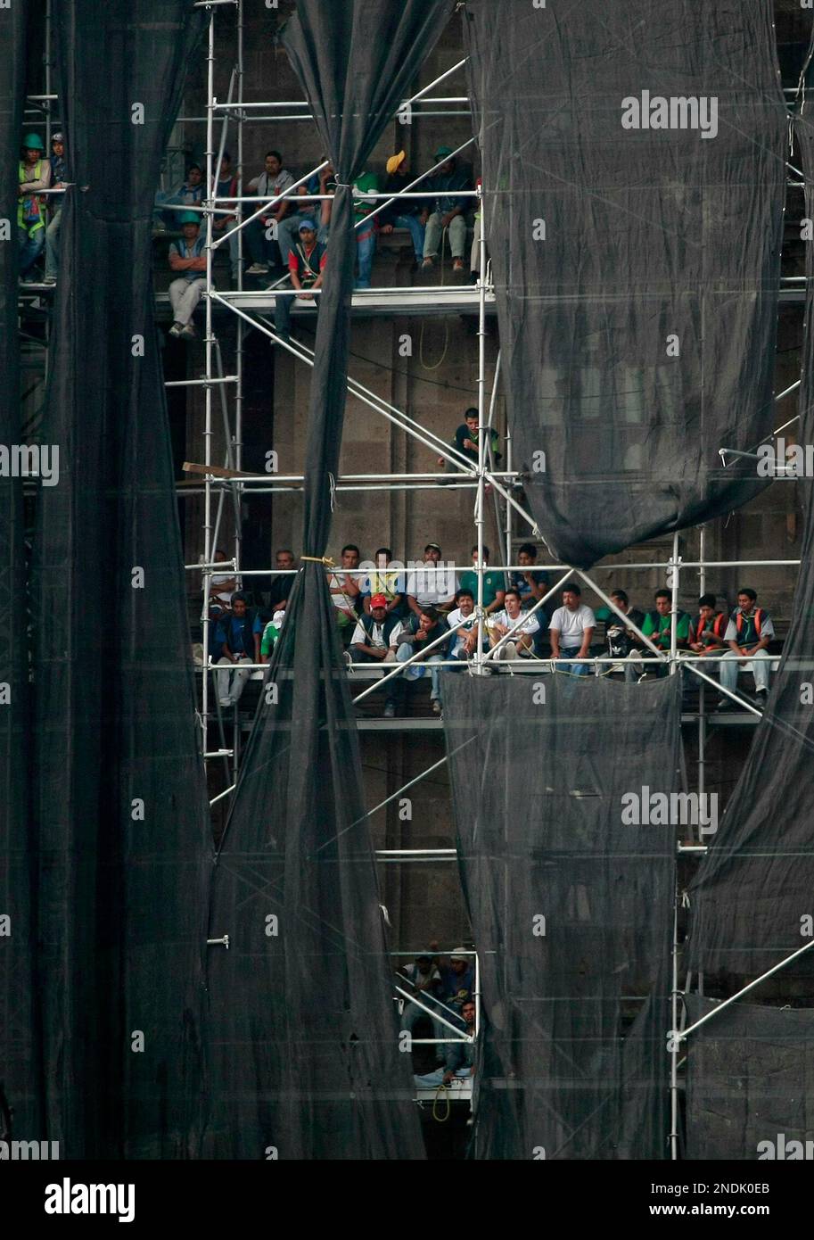Construction workers watch the inaugural World Cup 2010 soccer match between Mexico and South Africa on a giant screen at Mexico City's Zocalo main plaza, Friday, June 11, 2010. The game ended tied 1-1. (AP Photo/Eduardo Verdugo) Stockfoto