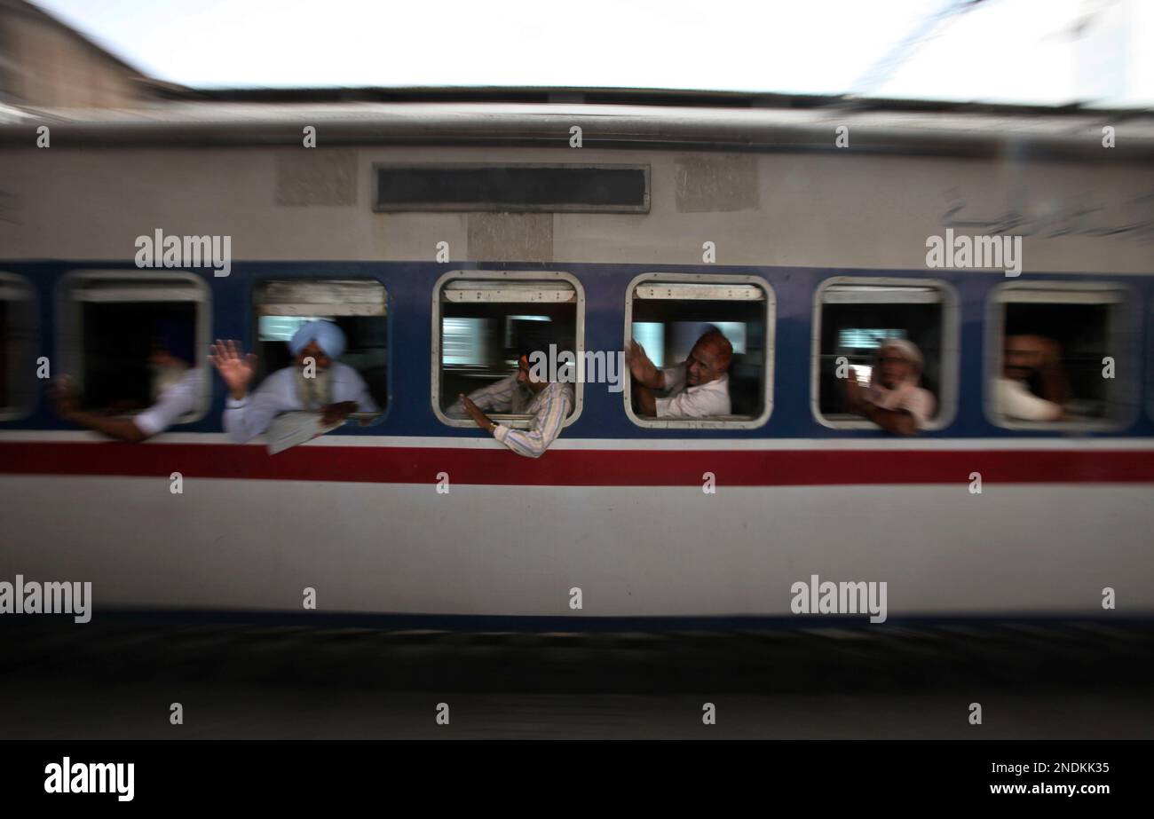 Sikh pilgrims wave from inside a special train to Pakistan as it leaves the train station in Amritsar, India, Tuesday, June 8, 2010. A group of Sikh pilgrims left for Pakistan where they will commemorate the Martyrdom Day of Guru Arjun Dev in Lahore on June 16. (AP Photo/Altaf Qadri) Stockfoto