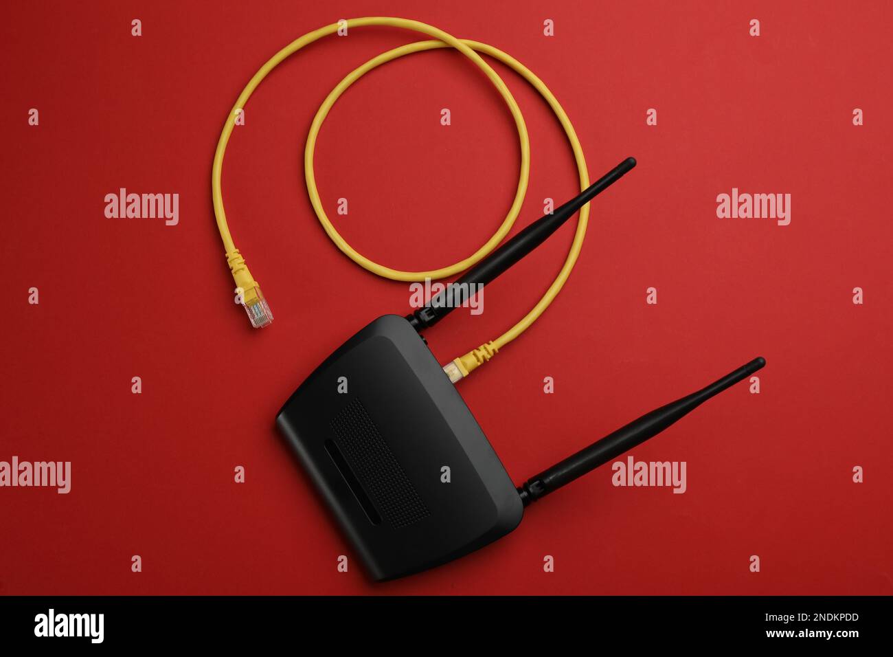 Moderner WLAN-Router mit Kabel auf rotem Hintergrund, Draufsicht Stockfoto