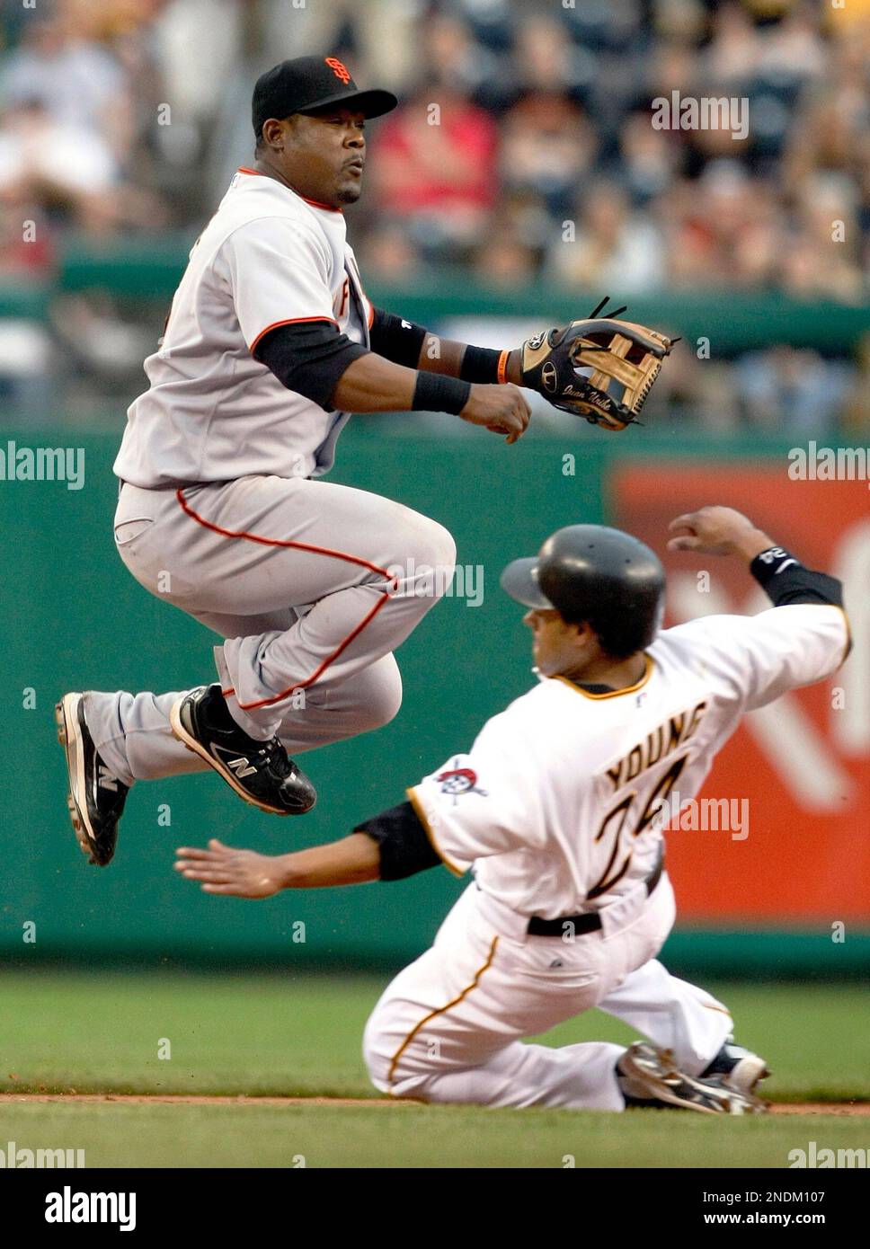 San Francisco Giants shortstop Juan Uribe, left, hops over sliding Pittsburgh Pirates' Delwyn Young to complete the double play on Andy LaRoche in the third inning of the baseball game in Pittsburgh, Saturday, June 5, 2010. (AP Photo/Keith Srakocic) Stockfoto