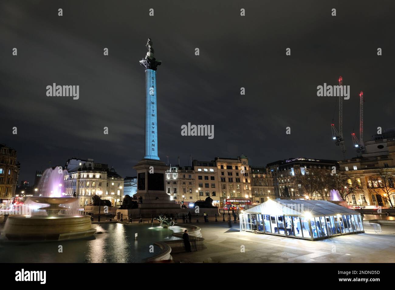 London, Großbritannien. 15. Februar 2023. Nelson's Column wird im Syria's House beleuchtet, einem bis Freitag geöffneten Gemeindezelt, das das Bewusstsein schärfen und einen Raum bieten soll, in dem Menschen zusammenkommen und sich an die in der Tragödie verlorenen Angehörigen erinnern können. Abends finden während der drei Tage, an denen das Zelt geöffnet ist, Nachtwachen bei Kerzenschein statt. Kredit: Elfte Stunde Fotografie/Alamy Live News Stockfoto