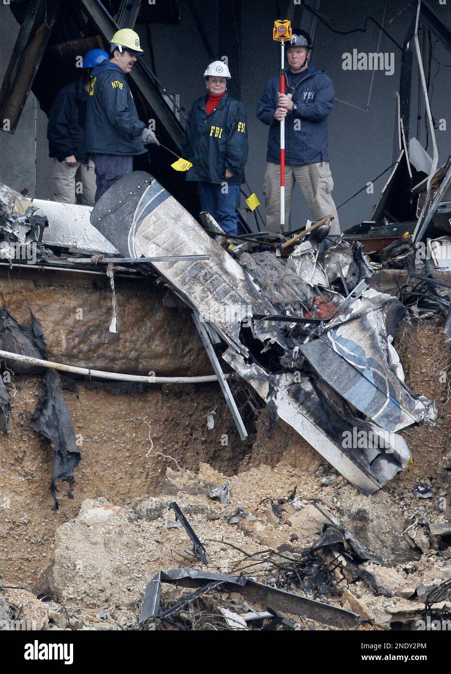 FILE - In this Feb. 19, 2010 file photo, NTSB and FBI investigators search through the aircraft wreckage inside an IRS office building in Austin, Texas. In 911 recordings released Monday, April 19, 2010, by the Austin Police Department callers describe the chaos after seeing and hearing a fiery plane crash at the office building that housed IRS offices. (AP Photo/Tony Gutierrez) Stockfoto