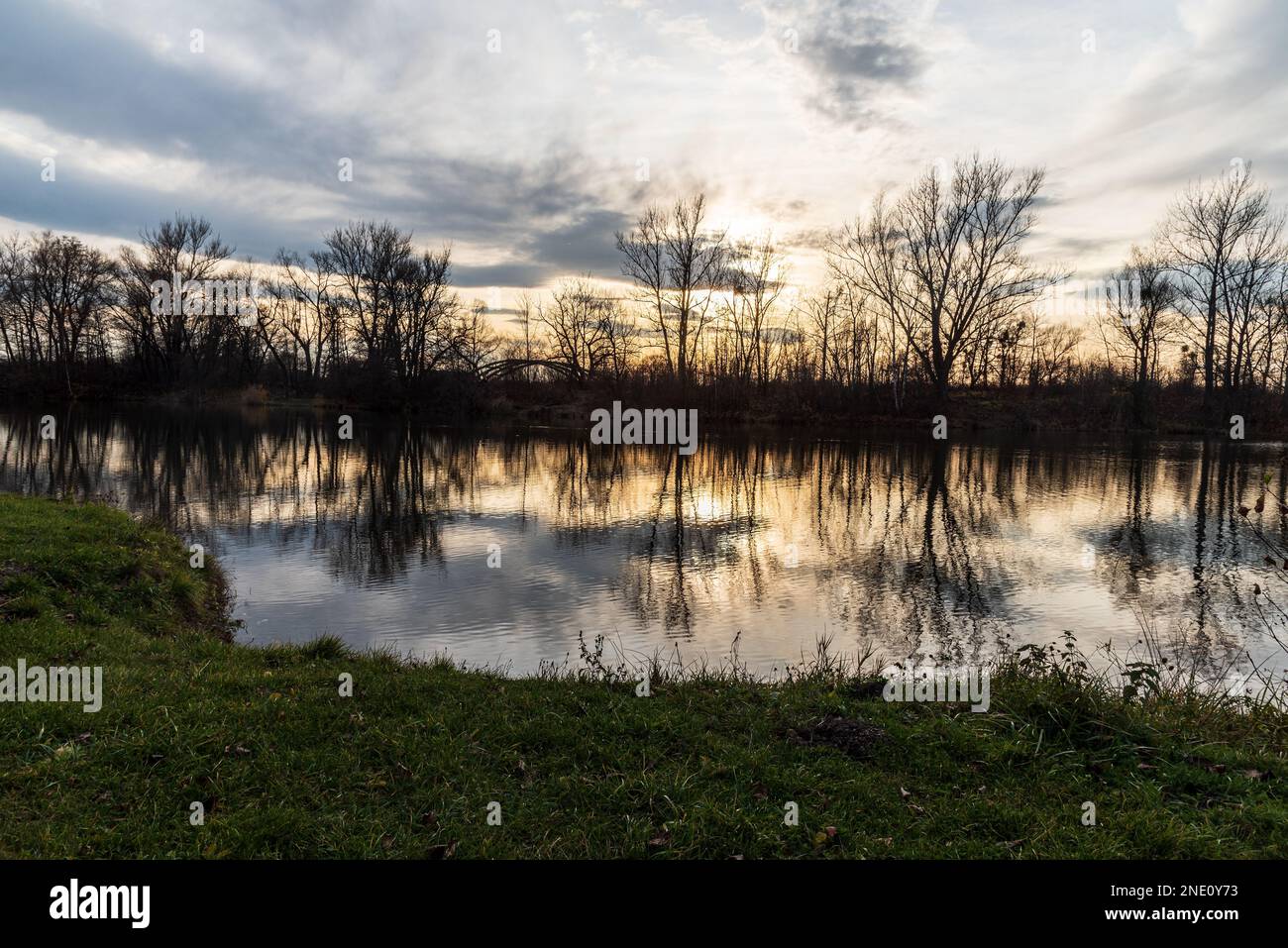 Teich mit Bäumen, die sich während des Herbstuntergangs auf dem Wasser im Park Bozeny Nemcove in Karvina in der tschechischen republik befinden Stockfoto