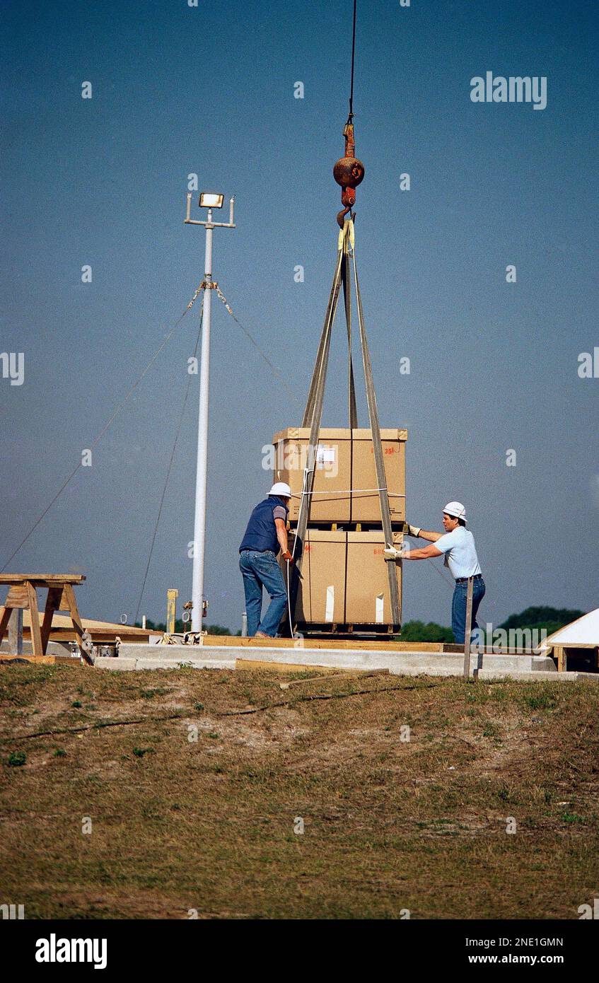 Workmen shift a huge crate containing debris from the Space Shuttle