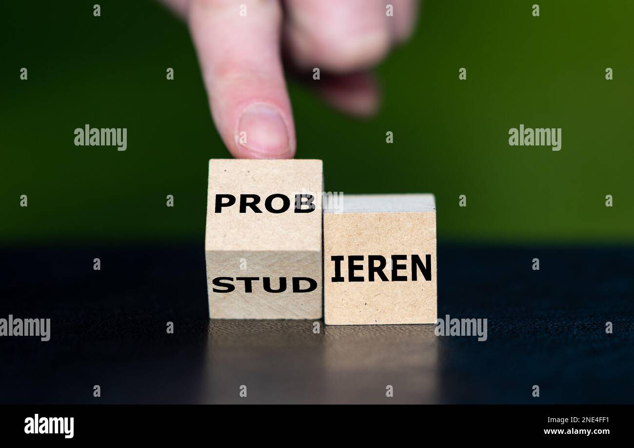 Die Hand dreht Holzwürfel um und ändert das deutsche Wort „tudieren“ (Studie) in „probieren“ (Versuch). „Learning by Doing“-Konzept. Stockfoto