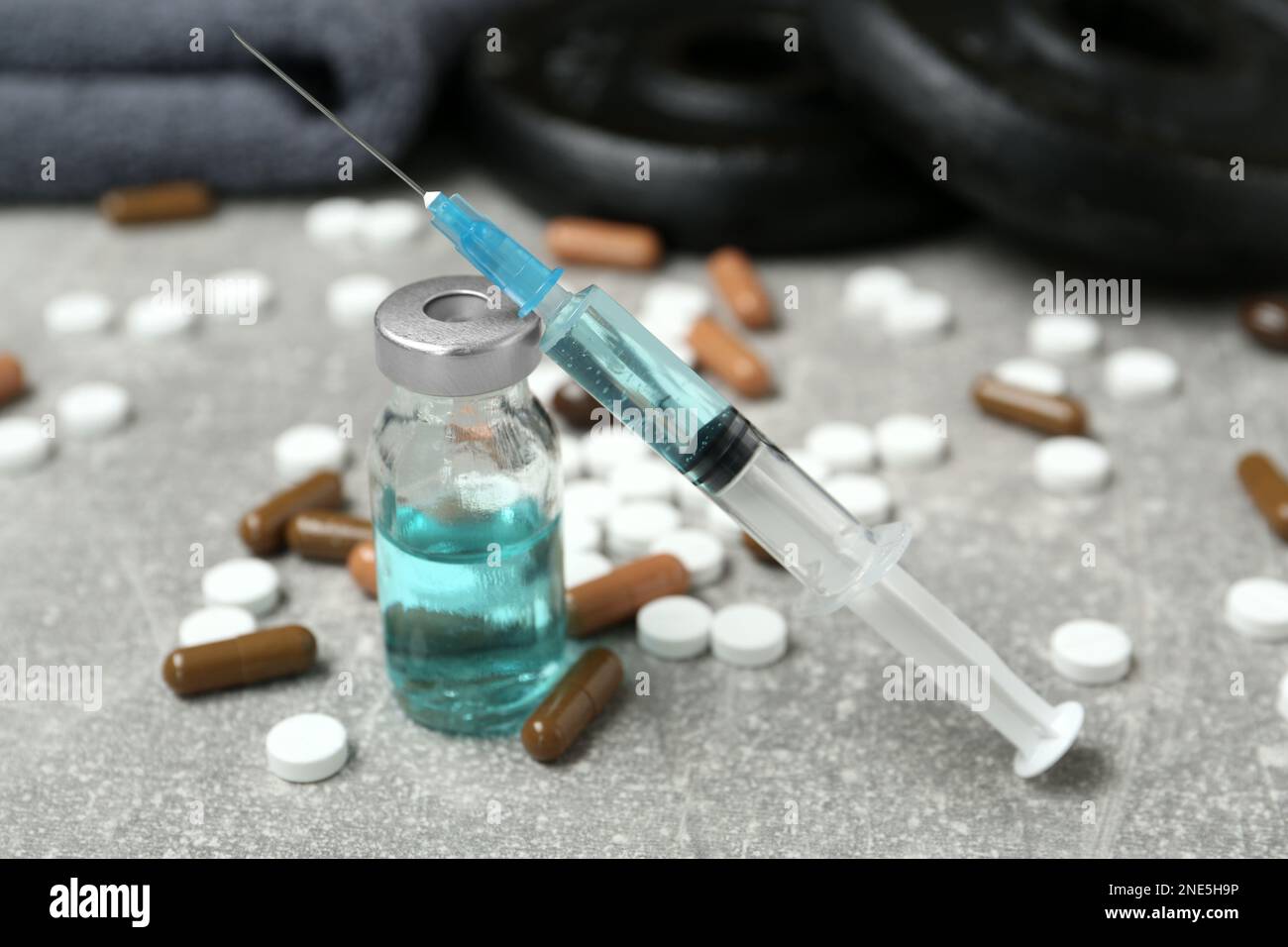 Verschiedene Medikamente in der Nähe von Sportgeräten auf einem hellgrauen Tisch. Dopingkontrolle Stockfoto