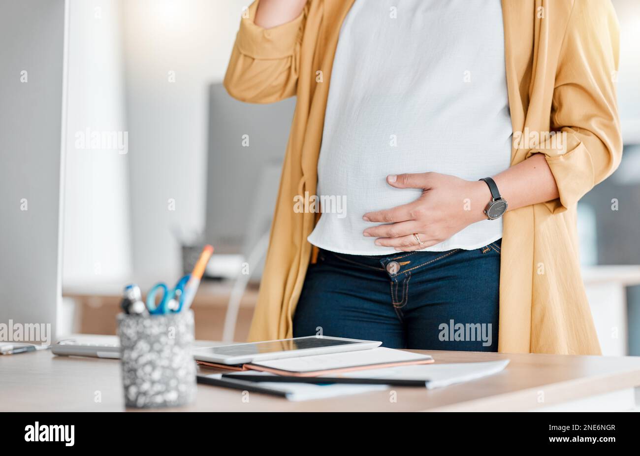 Schwangerschaft, Hand und Magen am Arbeitsplatz mit Tablet, Telefonat und Selbstversorgung für zukünftige mütter. Schwangere Frau, Schreibtisch oder Kommunikation in der Öffentlichkeit Stockfoto