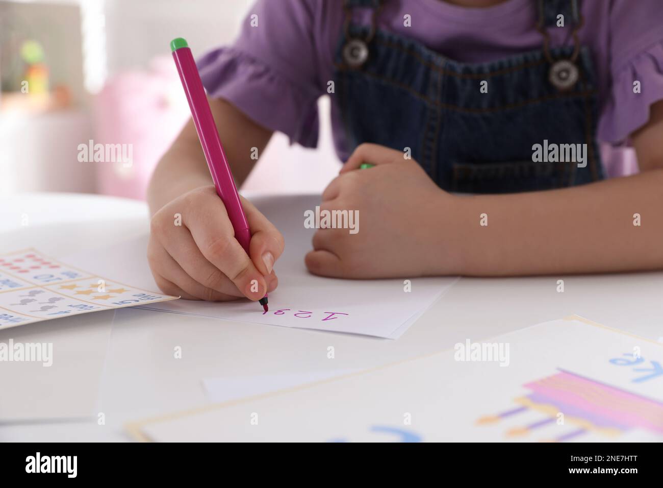 Ein kleines Mädchen schreibt Zahlen im Unterricht beim Englischunterricht, Nahaufnahme Stockfoto