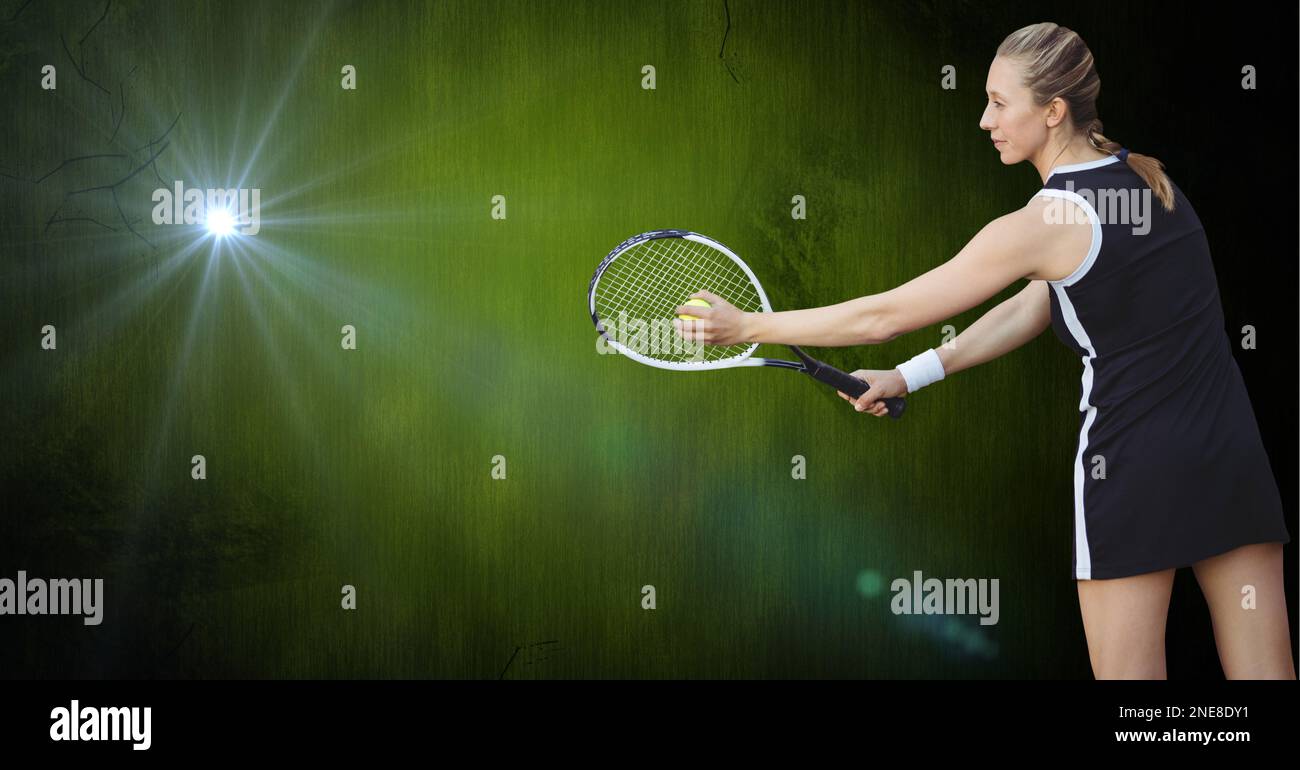 Weiße Tennisspielerin, die vor hellem Licht auf grünem Hintergrund einen Aufschlag macht Stockfoto