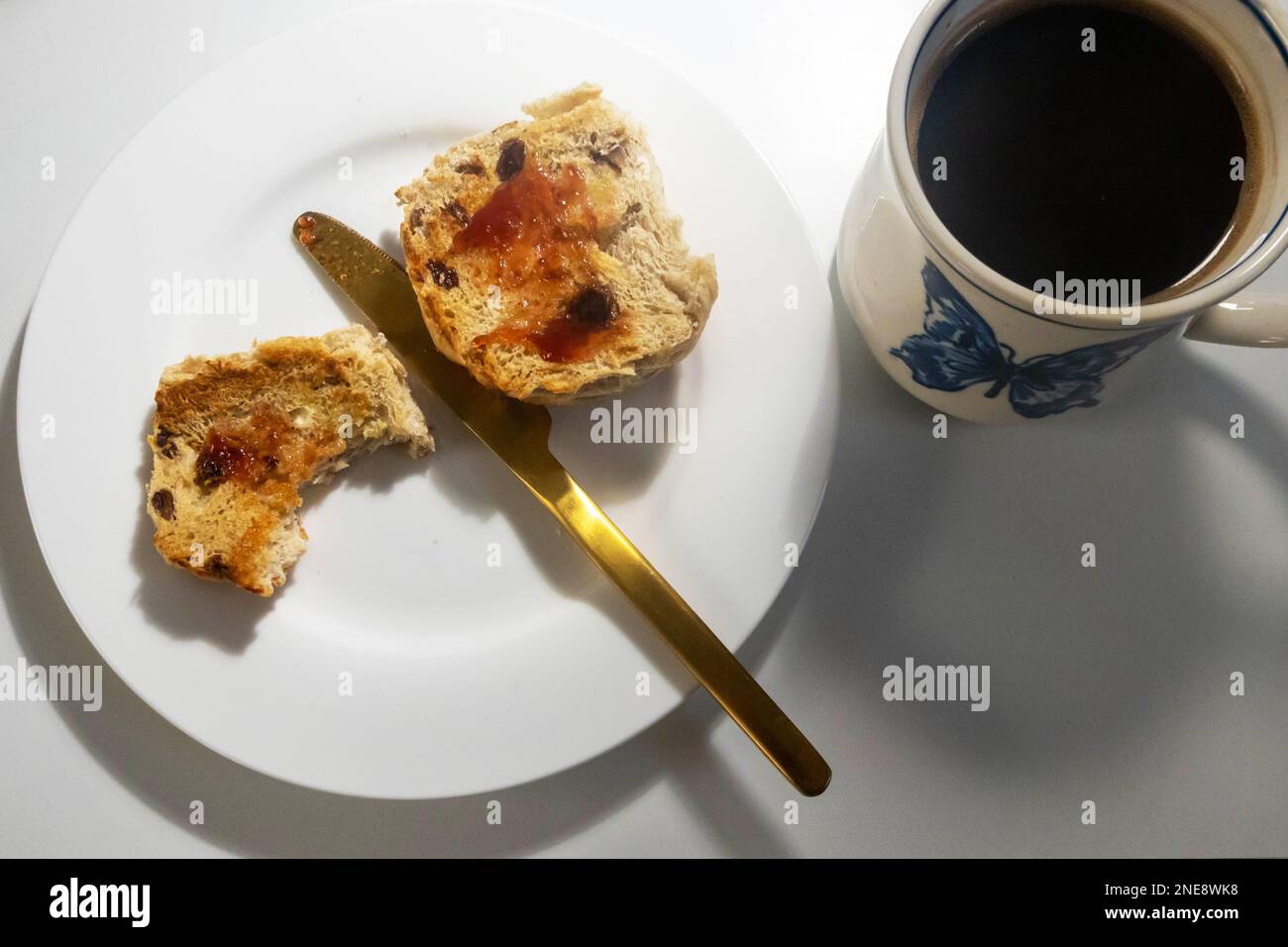 Getoastetes heißes Brötchen mit Marmelade und schwarzem Kaffee Stockfoto