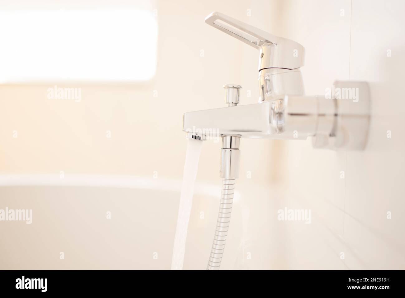 Fließendes Wasser eines Wasserhahns in einem hellen Badezimmer - selektiver Fokus Stockfoto