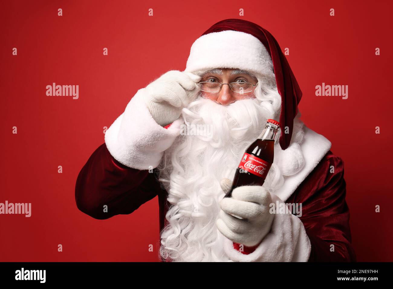 MYKOLAIV, UKRAINE - 18. JANUAR 2021: Santa Claus hält Coca-Cola-Flasche auf rotem Hintergrund Stockfoto