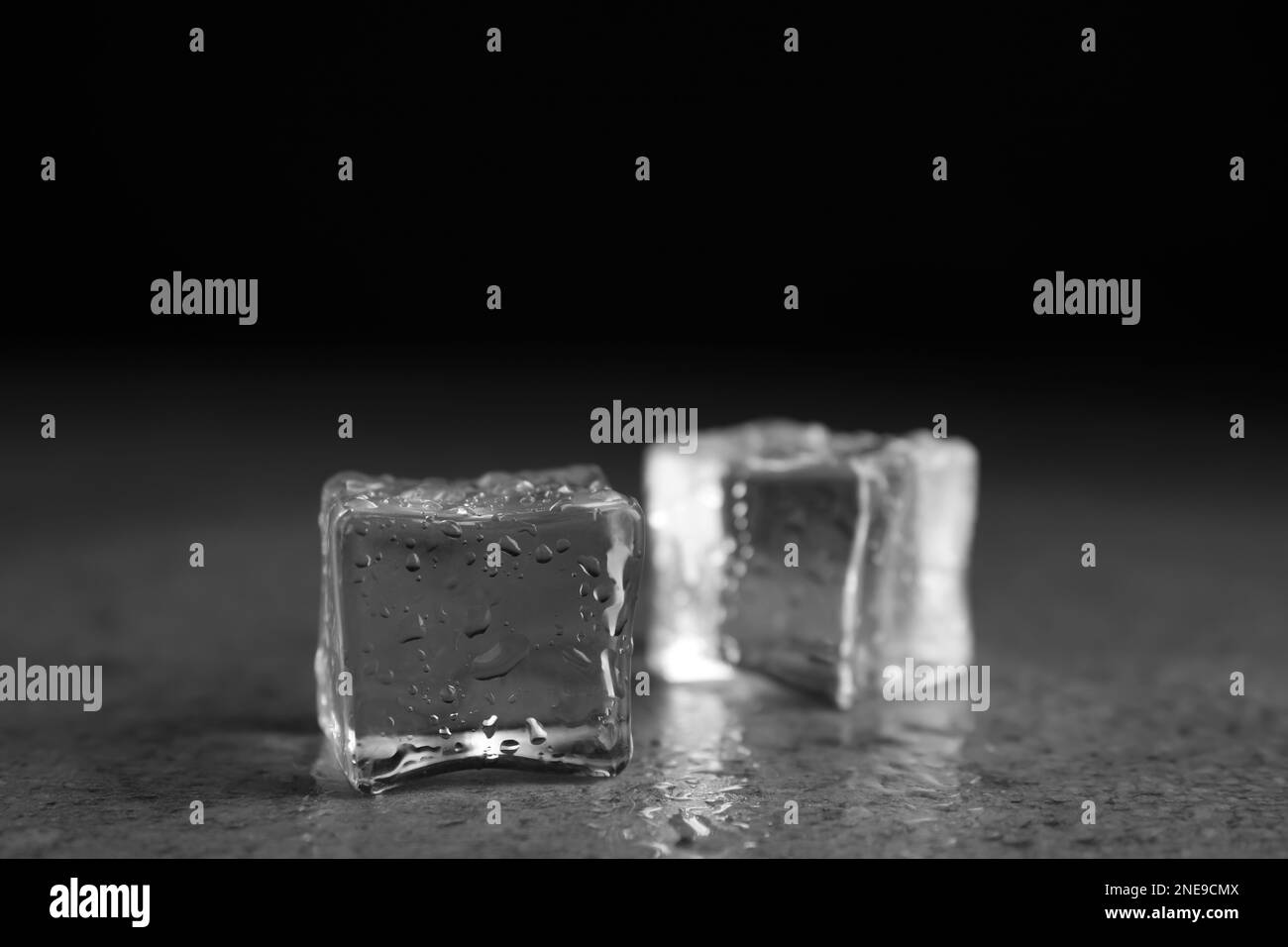 Eiswürfel mit Wassertropfen auf grauem Steintisch, Nahaufnahme Stockfoto