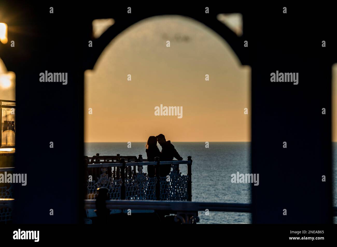 Young love on Brighton Palace Pier mit Blick auf den Sonnenuntergang, Sussex, England Großbritannien Stockfoto