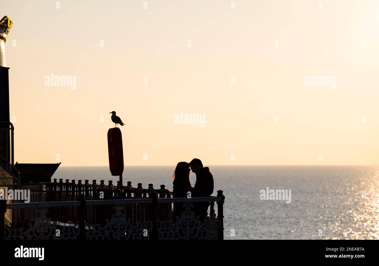 Young love on Brighton Palace Pier mit Blick auf den Sonnenuntergang, Sussex, England Großbritannien Stockfoto