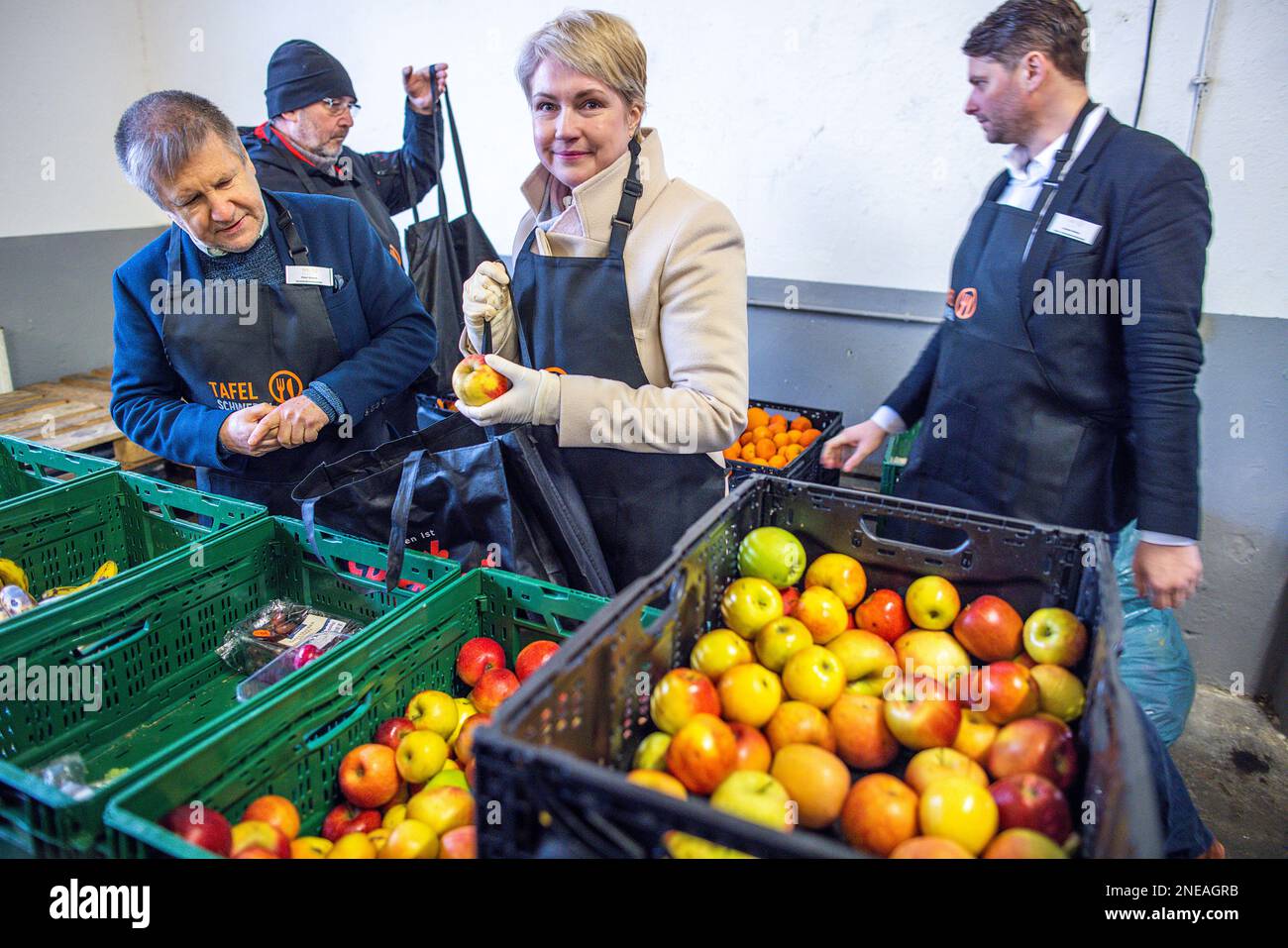 Schwerin, Deutschland. 16. Februar 2023. Manuela Schwesig (SPD, M), Ministerpräsidentin von Mecklenburg-Vorpommern, steht neben Peter Grosch (l), Schweriner Tafel. Schwesig hilft Freiwilligen an der Schweriner Tafel beim Sortieren und Verpacken von Essen. Die Ministerpräsidentin betont die Bedeutung sozialer Institutionen in Krisenzeiten und dankt den dort tätigen Freiwilligen. Angesichts der derzeit hohen Inflation kommt den staatlichen Lebensmittelbanken eine besondere Rolle zu, wenn es darum geht, einkommensschwache Haushalte mit Grundnahrungsmitteln auszustatten. Kredit: Jens Büttner/dpa/Alamy Live News Stockfoto