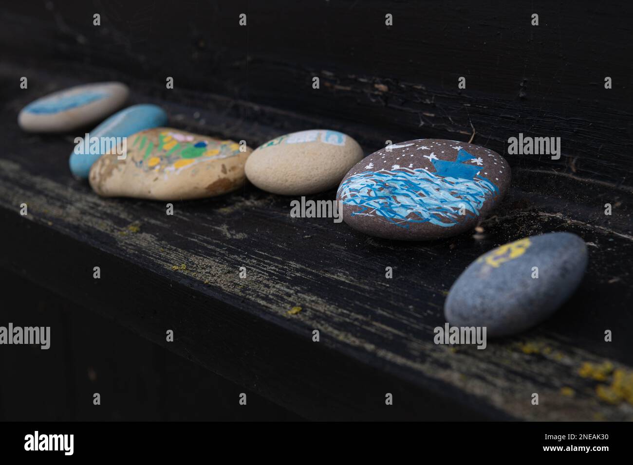 Bunte, bemalte Steine auf einer schwarzen Strandhütte in Walberswick, Suffolk. Stockfoto