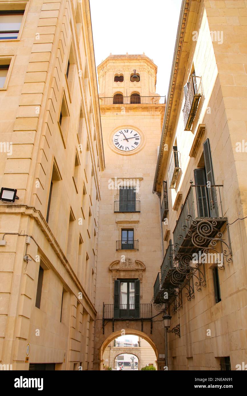 Blick hinter das Rathaus von Alicante. Uhrenturm über und schmale Gasse unter Ihnen, die zum Stadtplatz oder plaza in Alicante, Spanien führt. Stockfoto
