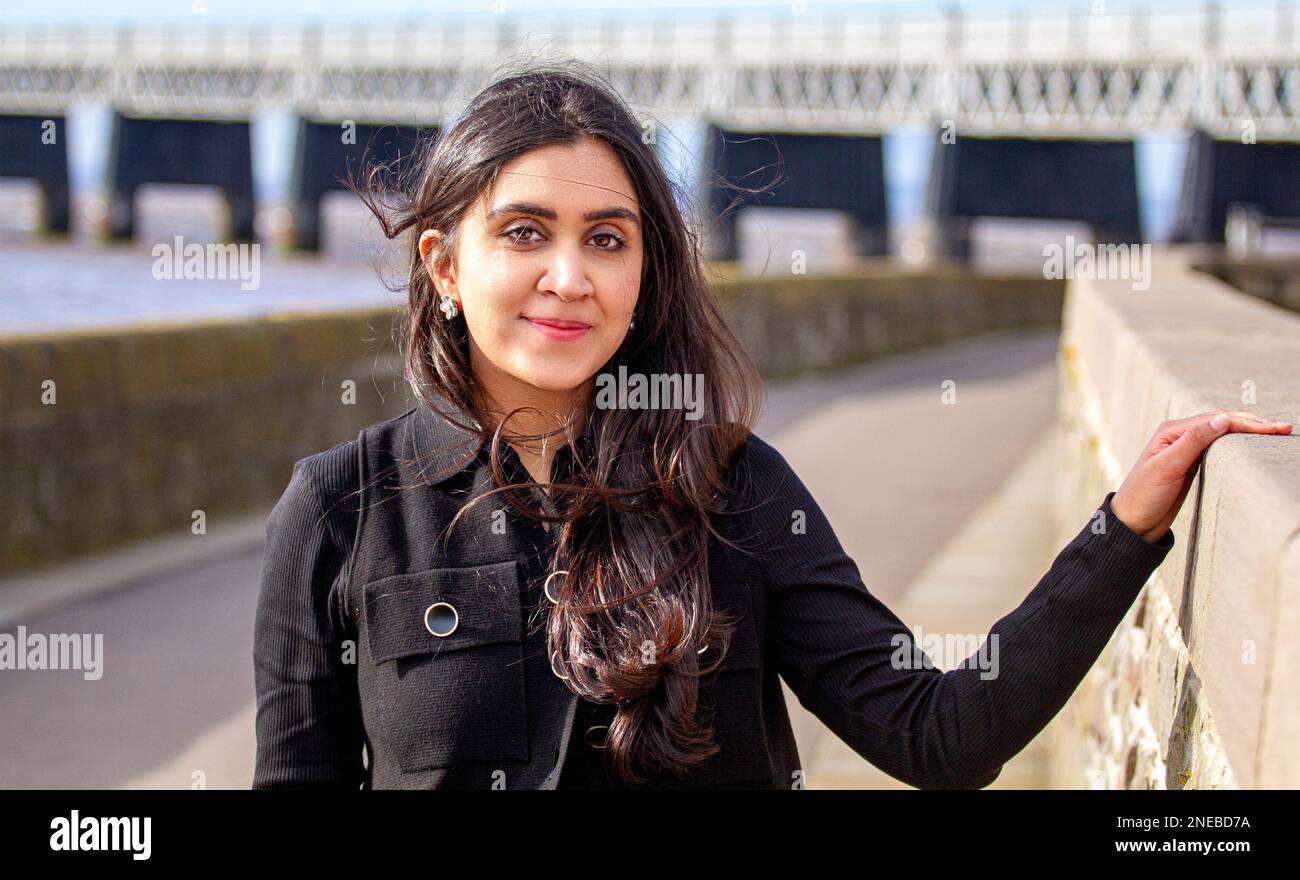 Eine wunderschöne und modische Frau verbringt den Tag damit, dass sie an einem sehr windigen Tag in Schottland, Großbritannien, entlang Dundee's Riverside fotografiert wird Stockfoto