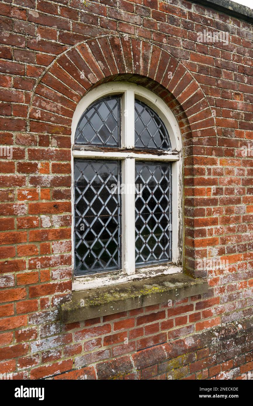 Kirchenbogenfenster mit bleihaltigem Glas, Fenster in einem verrotteten Holzrahmen Stockfoto