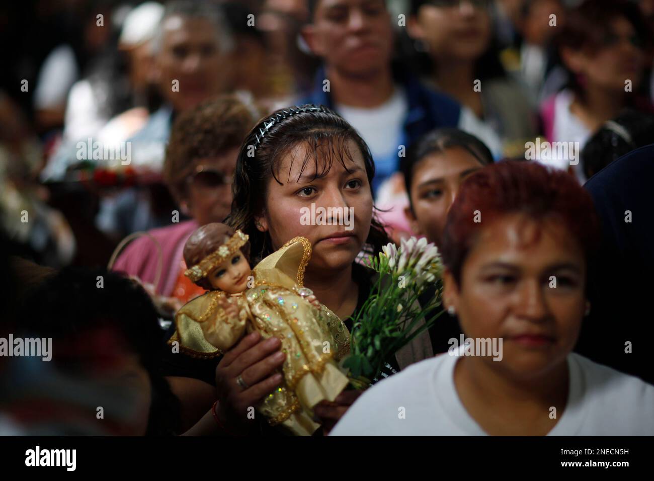 A woman holds a statue of the baby Jesus during a celebration of the