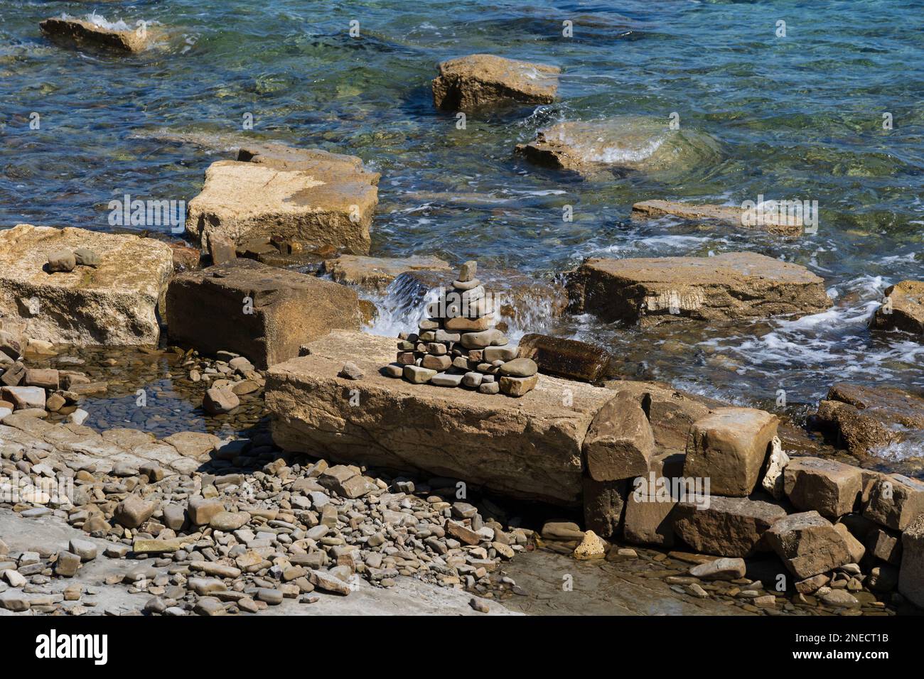 Pyramide aus Kieselsteinen am felsigen Ufer der Adria in Piran, Slowenien. Stockfoto