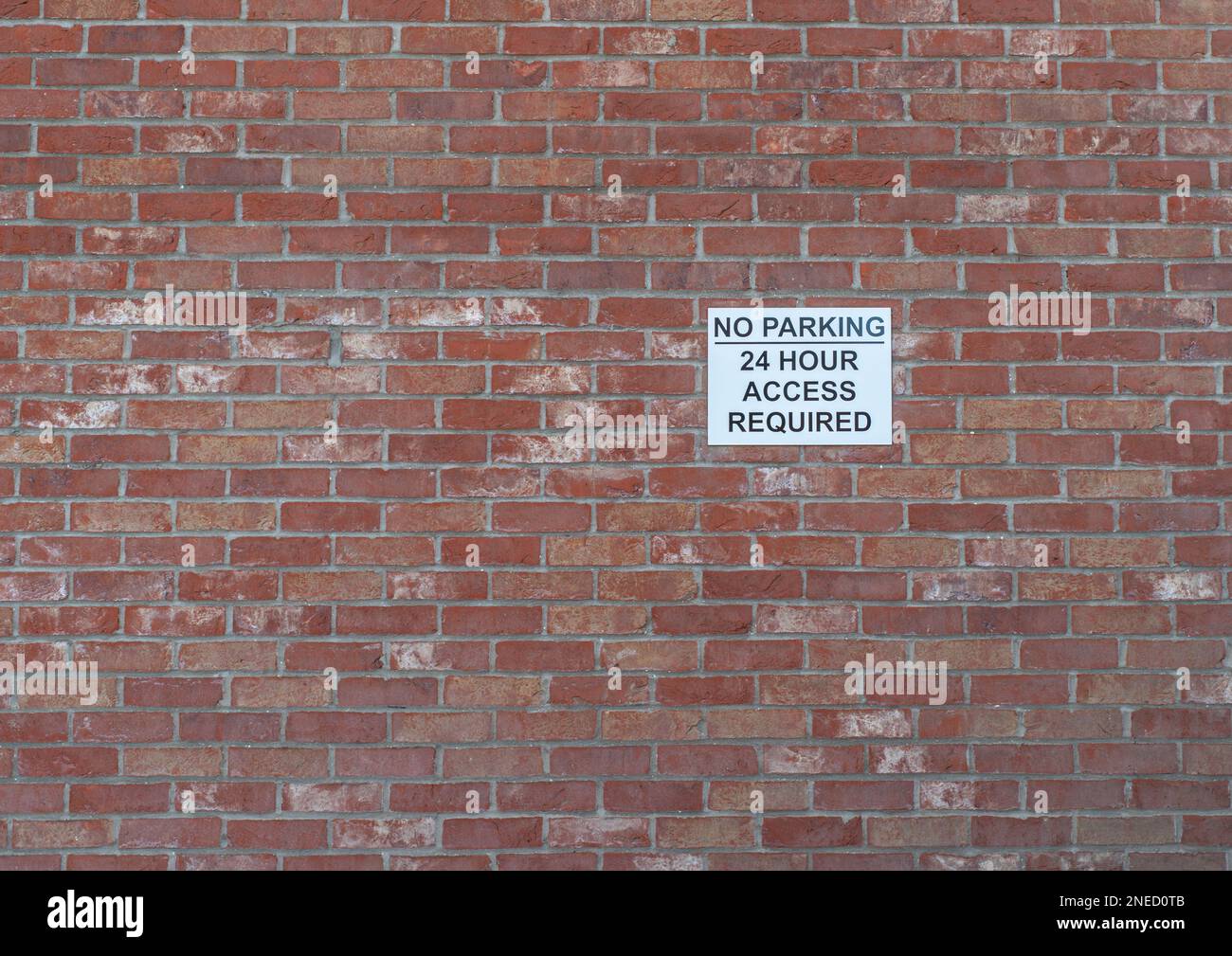 27. Januar 2022 - Ein schwarz-weißes Warnschild für keine Parkplätze und 24-Stunden-Zugang an einer roten Backsteinmauer. Stockfoto