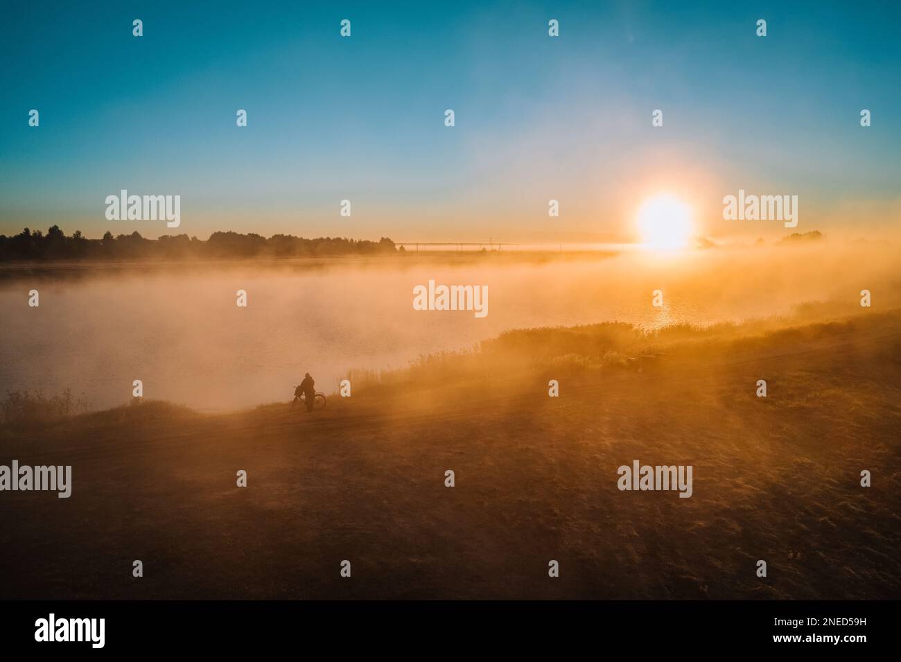 Wunderschöner mystischer Nebel im Herbst. Die Sonne scheint durch Nebel. Der Fischer steht in der Nähe des Sees im Nebel Stockfoto Wunderschöner mystischer Nebel im Herbst. Die Sonne scheint durch Nebel. Der Fischer steht in der Nähe des Sees im Nebel Stockfoto