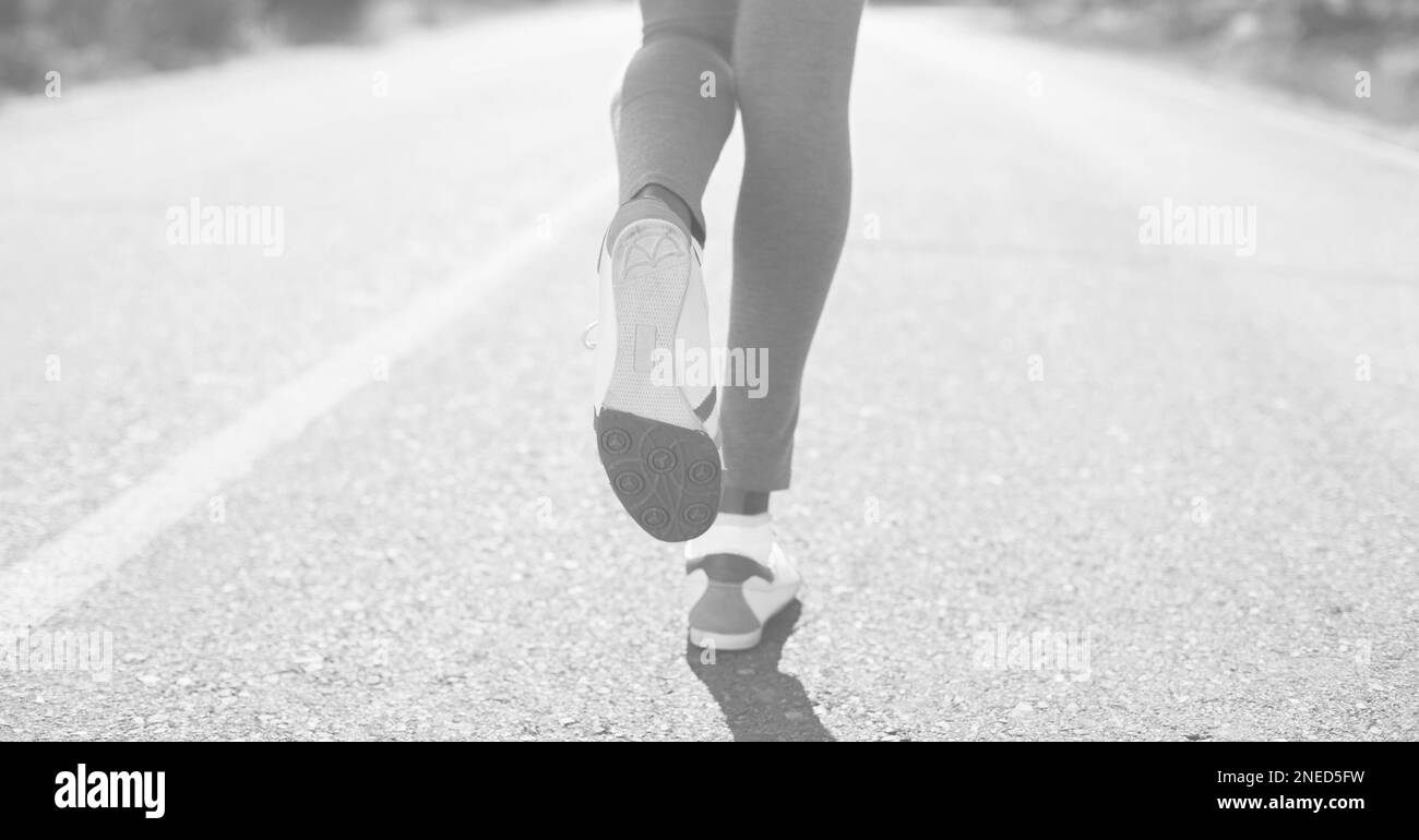 Die Zusammensetzung der Beine einer Frau, die in Schwarz-Weiß auf der Straße läuft. Digital generiertes Bild des Konzepts Sport, Fitness und aktiver Lifestyle. Stockfoto