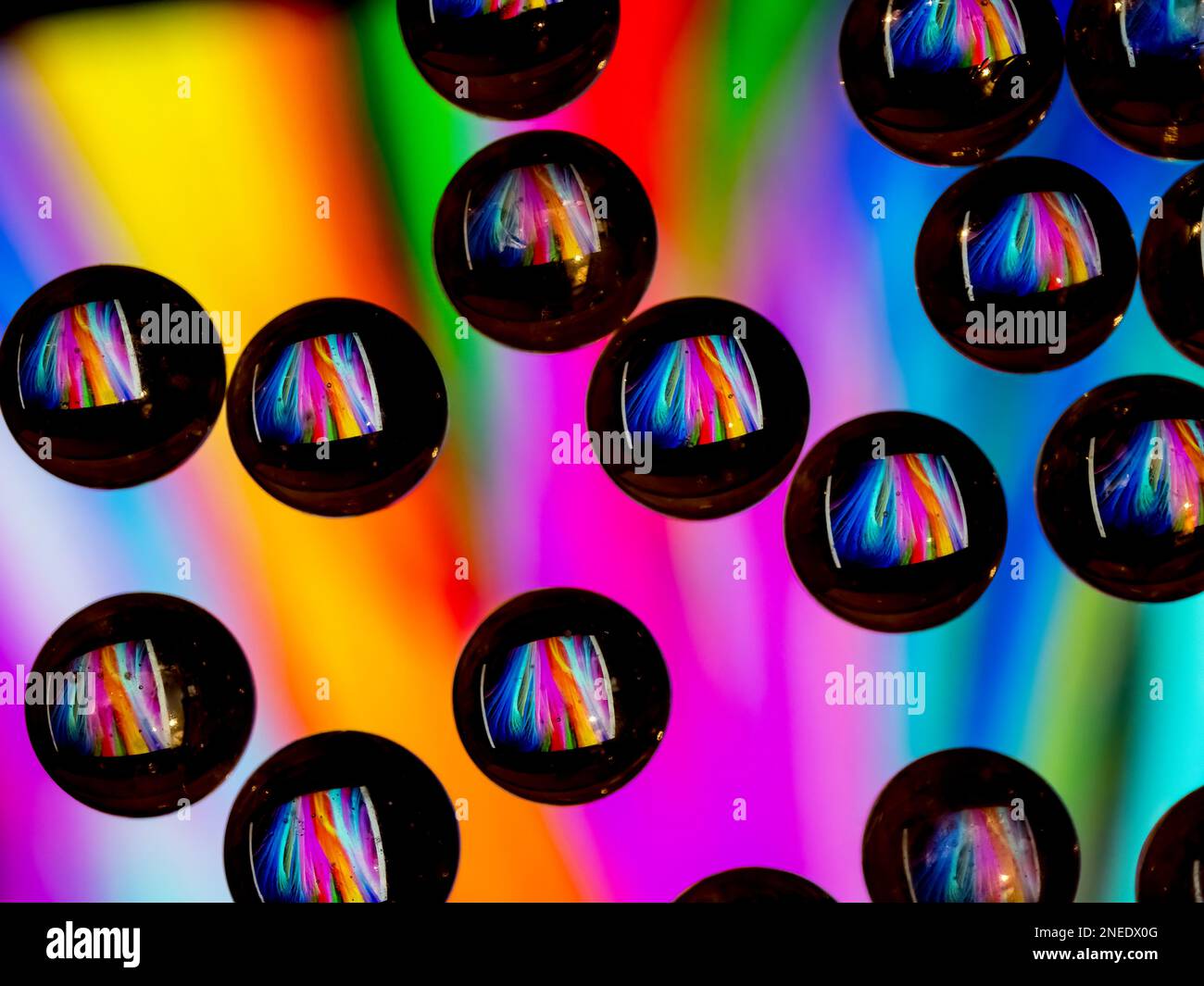 Farbenfrohes abstraktes Muster, das sich in schwarzen Tropfen aus ringförmigem Glas widerspiegelt Stockfoto