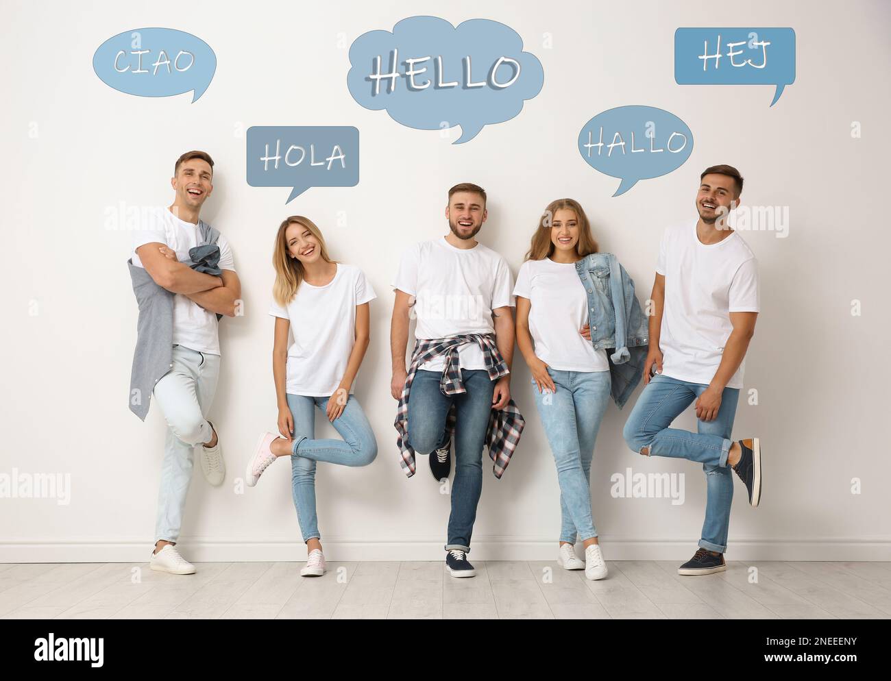 Fröhliche Leute, die neben einer hellen Wand posieren und Sprechblasen mit dem Wort „Hallo“ in verschiedenen Sprachen illustrieren Stockfoto