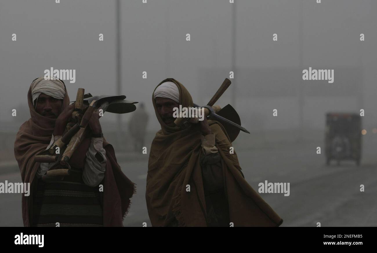 Pakistani labors are on their way to work as fog envelopes Lahore