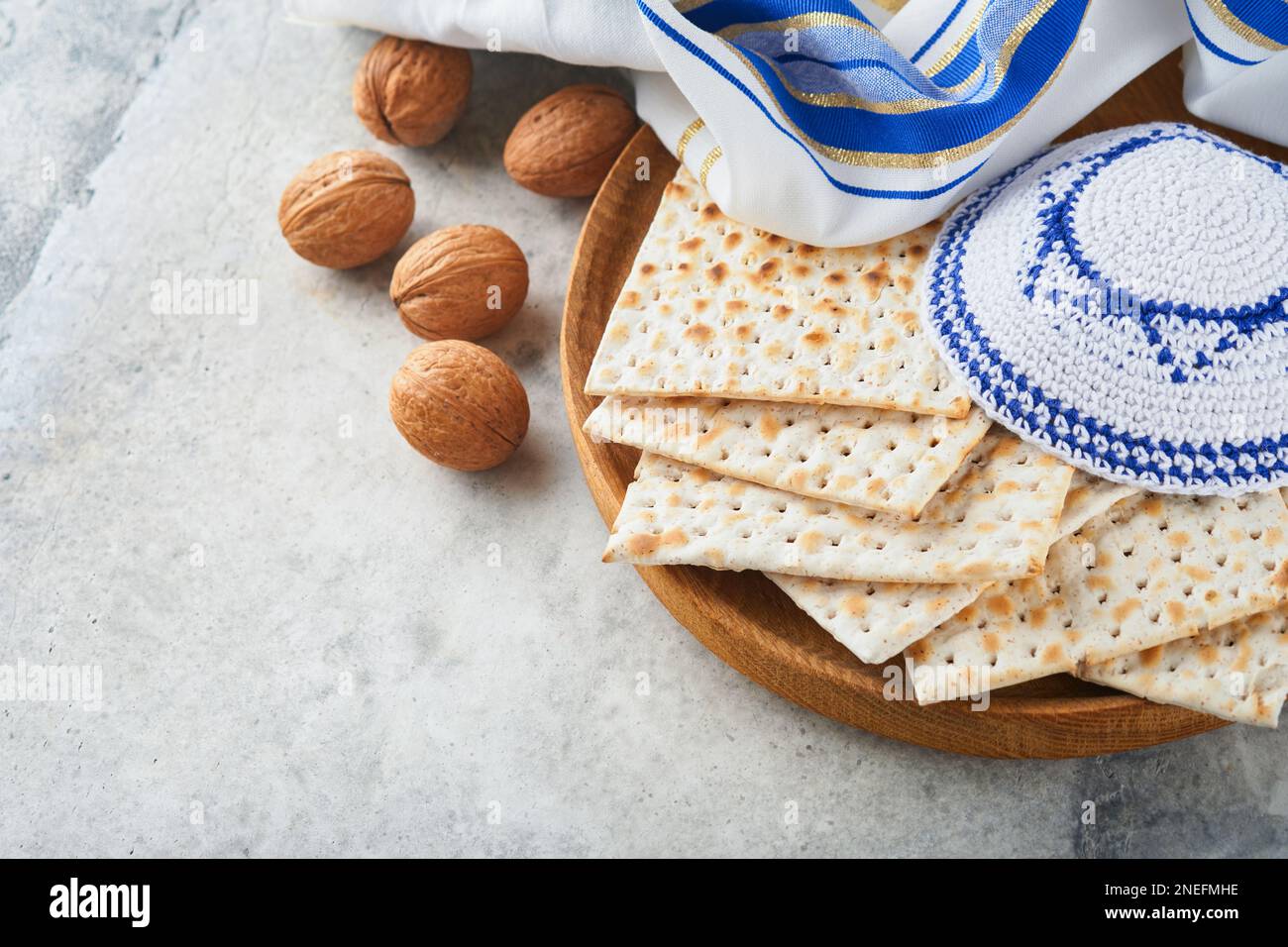 Das Konzept der Pessachstunde. Matzah, roter Koscher und Walnuss. Traditionelles jüdisches Brot Matzah, Kippah und Tallit auf altem Betonhintergrund. Pas Stockfoto