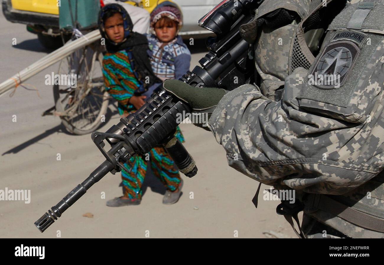Afghan children look at a soldier from the 293rd Military Police Company out of Fort Stewart, Ga., as he guards a checkpoint in Kandahar City, southern Afghanistan, Sunday, Jan. 17, 2010. (AP Photo/Kirsty Wigglesworth) Stockfoto