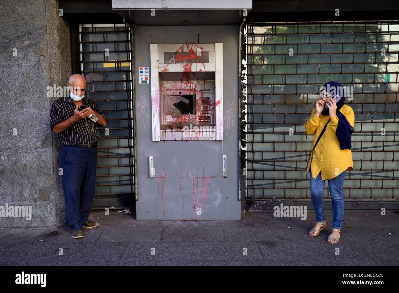 FILE - People waiting outside a Fransabank branch as they stand next to an ATM previously damaged in protests, in Beirut, on Sept. 26, 2022. Angry protesters in Lebanon Thursday Feb. 16, 2023 smashed windows and set tires on fire outside two of the country's biggest banks in the capital city, as the value of the local currency hit a new low and poverty deepens. (AP Photo/Bilal Hussein, File) Stockfoto