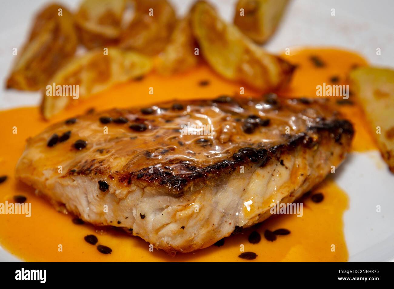 Traditioneller gegrillter Fisch (Wolfsbarsch) mit Passionsfruchtsauce. Nahaufnahme Stockfoto