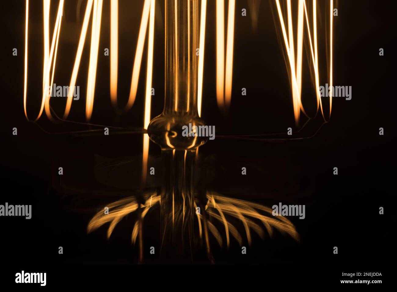 Details einer Wolframlampe, die im dunklen Hintergrund leuchtet, Makrofoto mit selektivem Weichzeichner Stockfoto