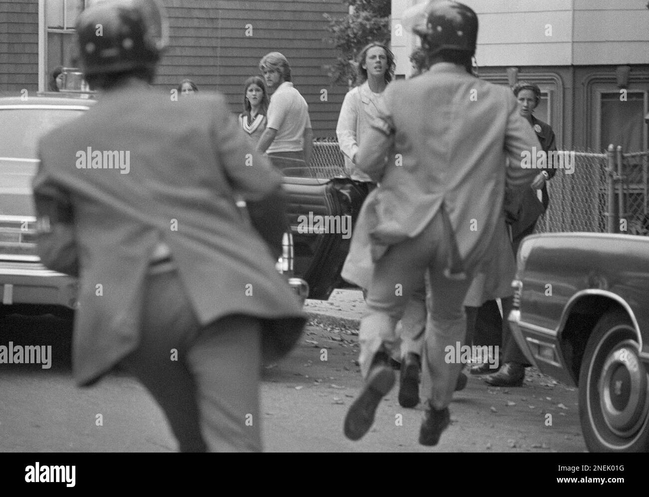 Riot-geared U.S. marshals close in on youths in South Boston on Friday, Sept. 19, 1975, and make their first arrest in Boston?s school integration controversy, the 16-year-old boy was charged with violation of a federal juvenile delinquency statute. The incident occurred as rock throwing broke out when police pushed a crowd of about 300 people away from South Boston High School as classes got out for the day. (AP Photo) Stockfoto