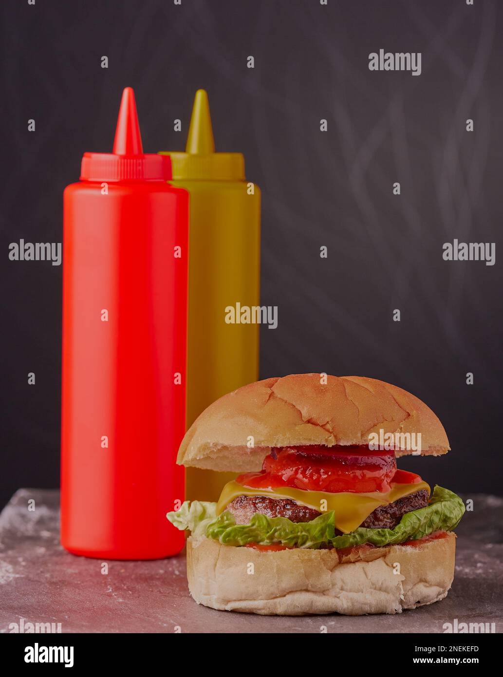 Saftiger Käse-Burger mit Senf und Ketchup im Hintergrund. Stockfoto