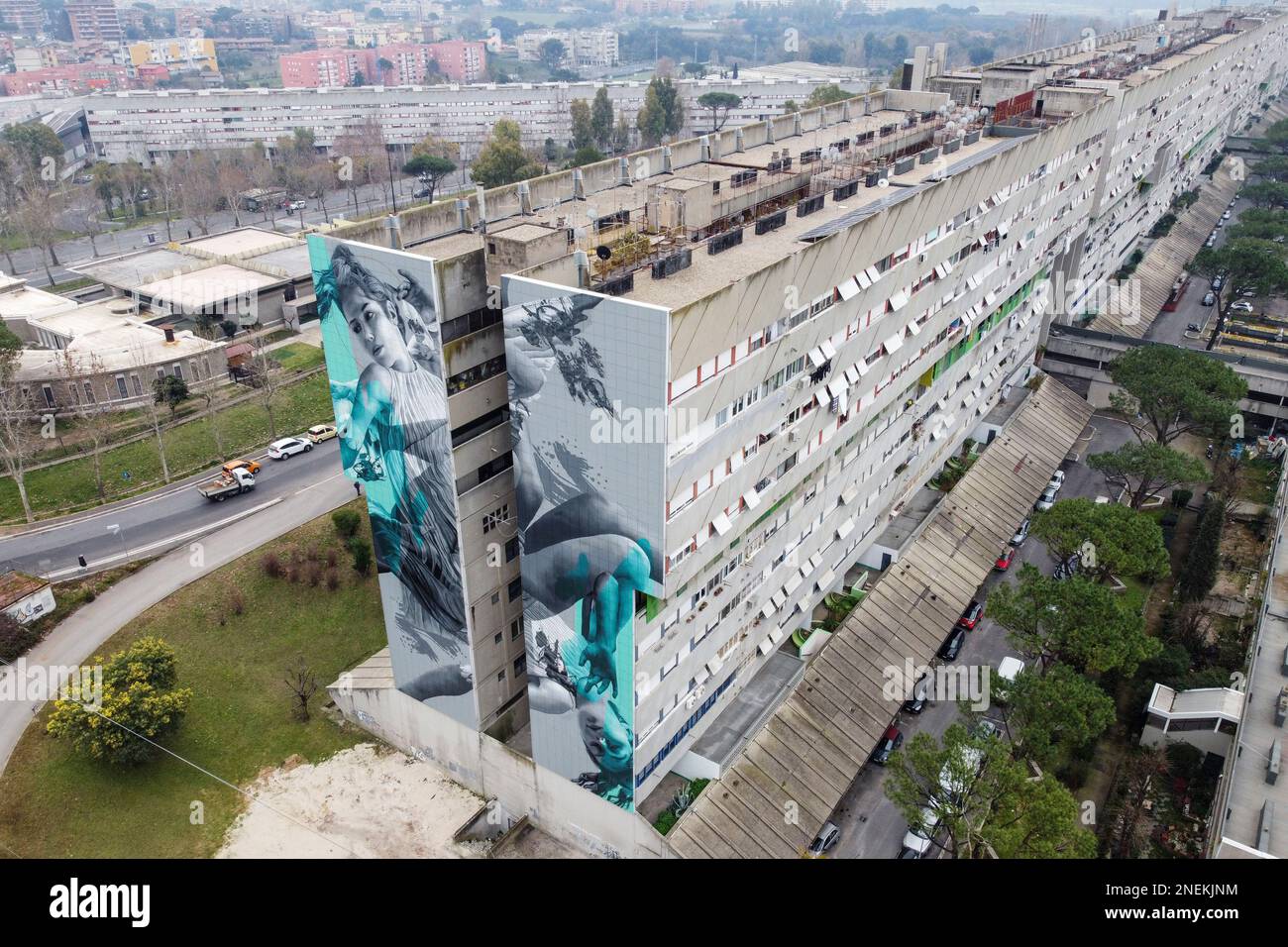 Rom, Italien. 16. Februar 2023. (ANMERKUNG DER REDAKTEURE: Bild mit Drohne aufgenommen).Ein 40 Meter langes Wandgemälde, das vom niederländischen Straßenkünstler JDL (Alter Ego des Künstlers Judith de Leeuw) an einer Wand der Corviale, einem 958 Meter langen öffentlichen Wohngebäude (aufgrund seiner Form auch als „die große Schlange“ bezeichnet) in Rom, geschaffen wurde. Das Thema ist inspiriert von dem Mythos von Ikarus, einer Metapher für eine Gesellschaft, die einem Weg folgen will, der dem prekären Schicksal des Klimas und der Umwelt wenig Aufmerksamkeit schenkt und zu Selbstzerstörung führt. (Kreditbild: © Stefano Costantino/SOPA Images via ZUMA Press Wire) E Stockfoto