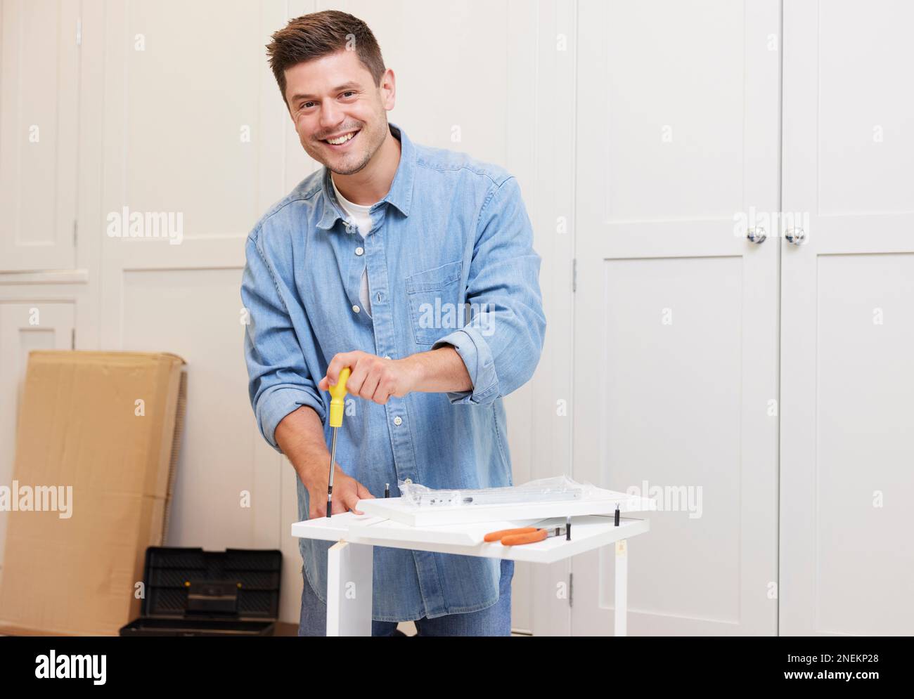 Portrait Of Man Putting Together Self Assembly Furniture At Home Stockfoto